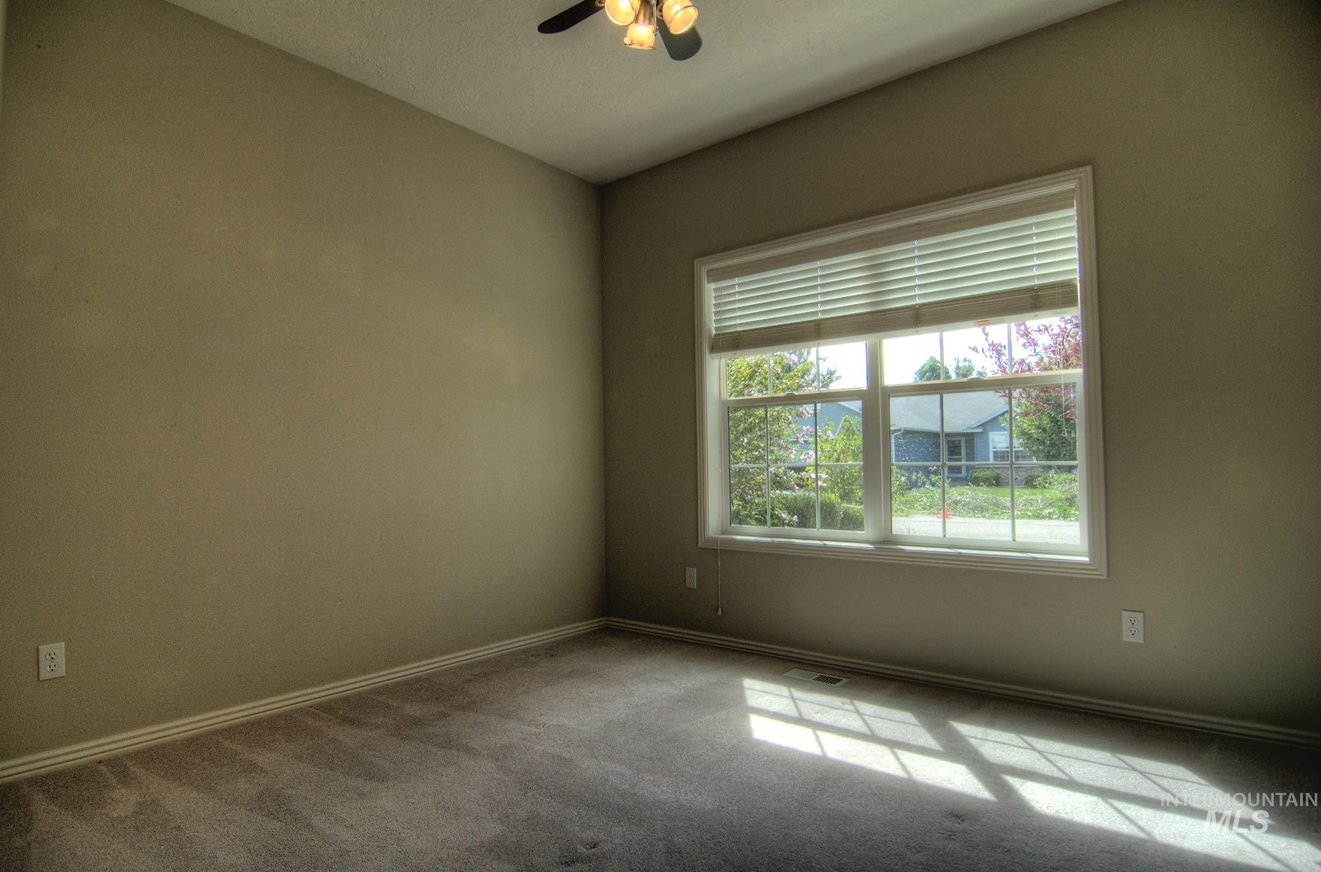 Carpeted spare room with baseboards and a ceiling fan