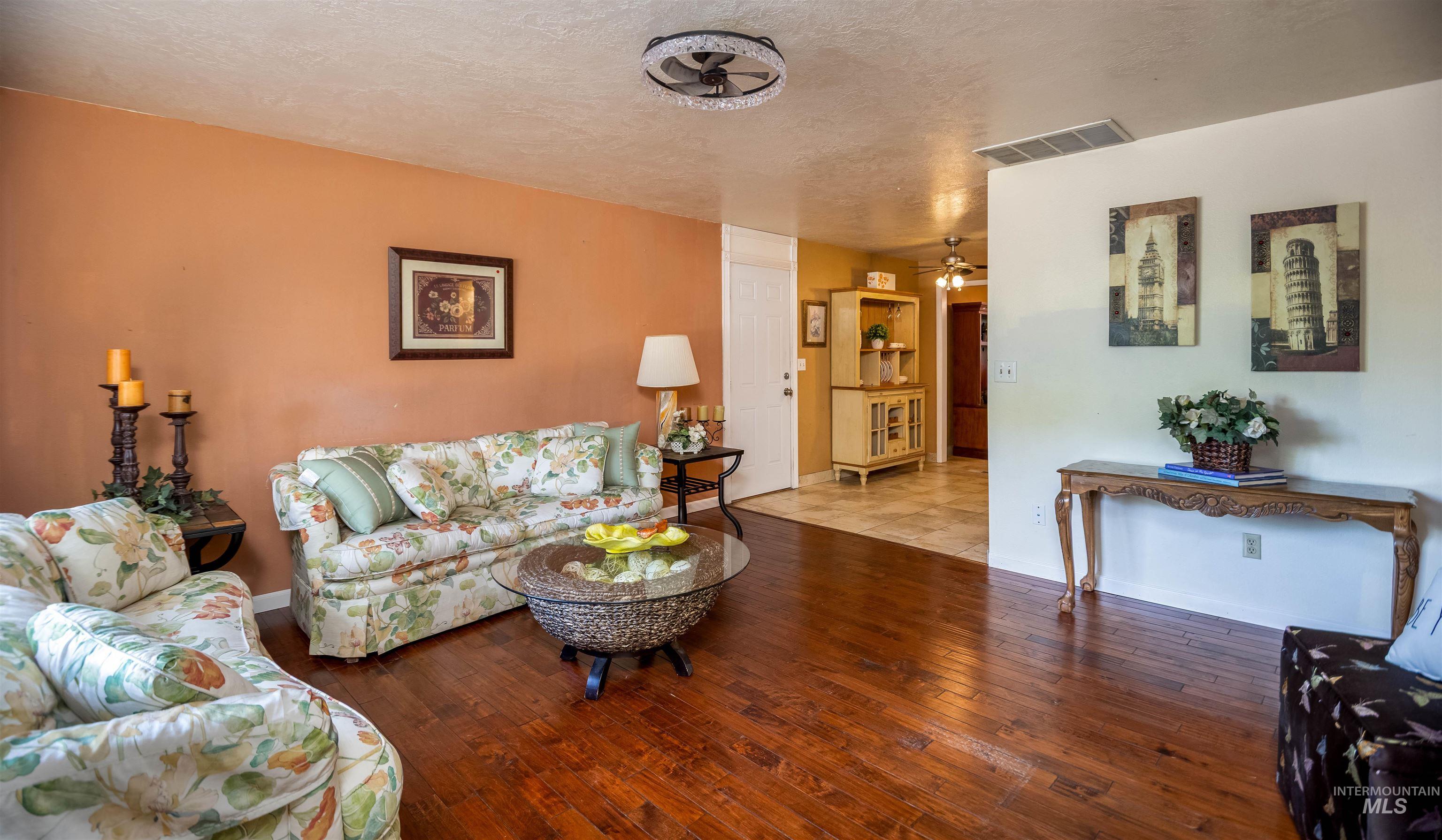 Living area featuring a textured ceiling, wood-type flooring, and ceiling fan
