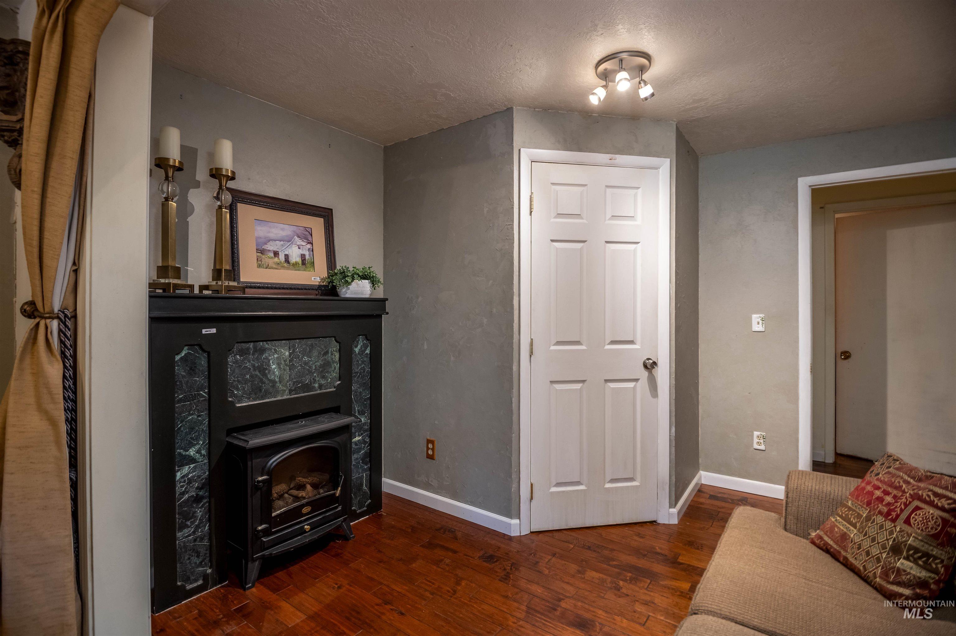 Living area featuring a wood stove, a textured ceiling, and dark wood finished floors