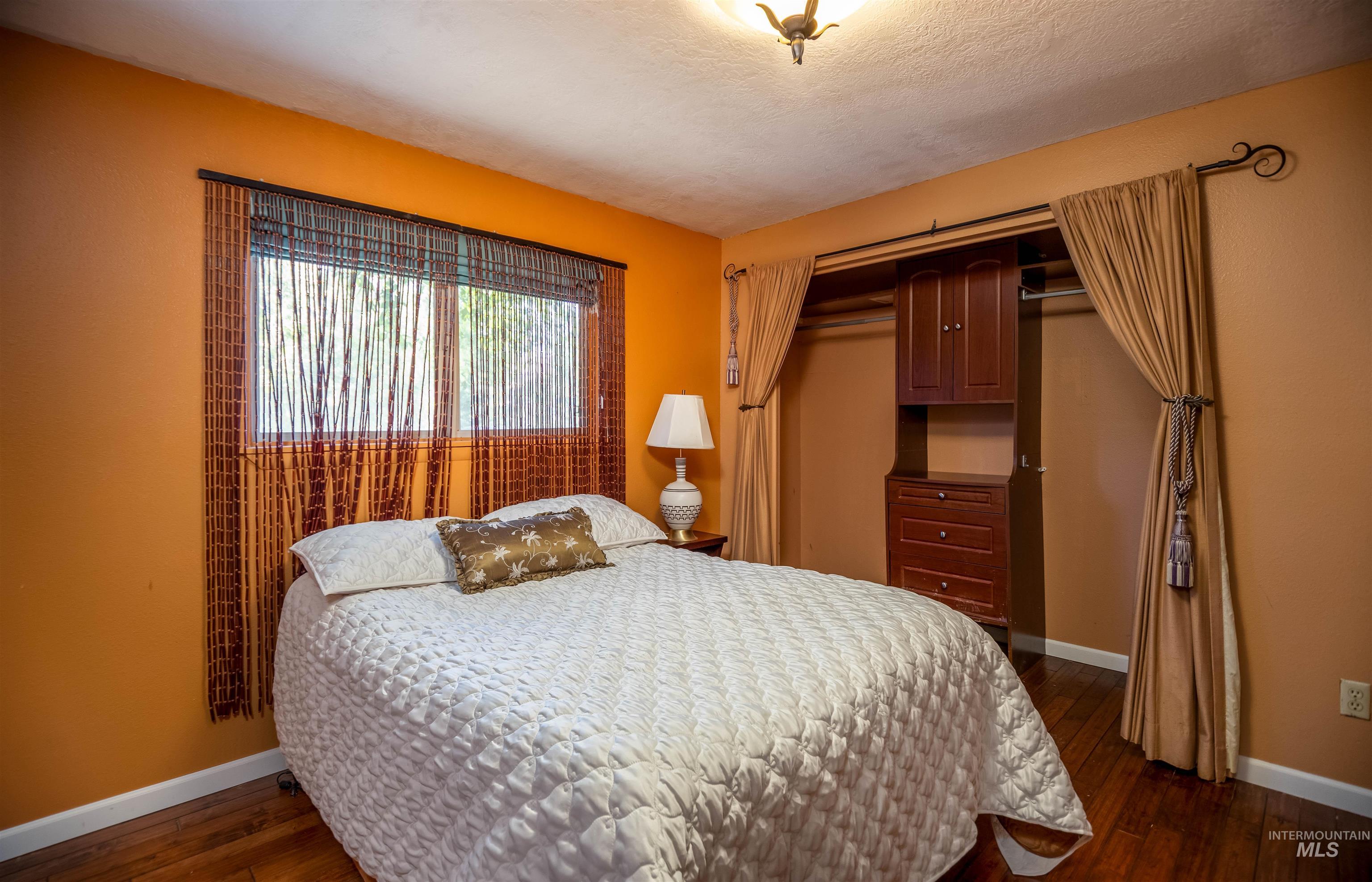 Bedroom with a closet, dark wood-type flooring, and a textured ceiling