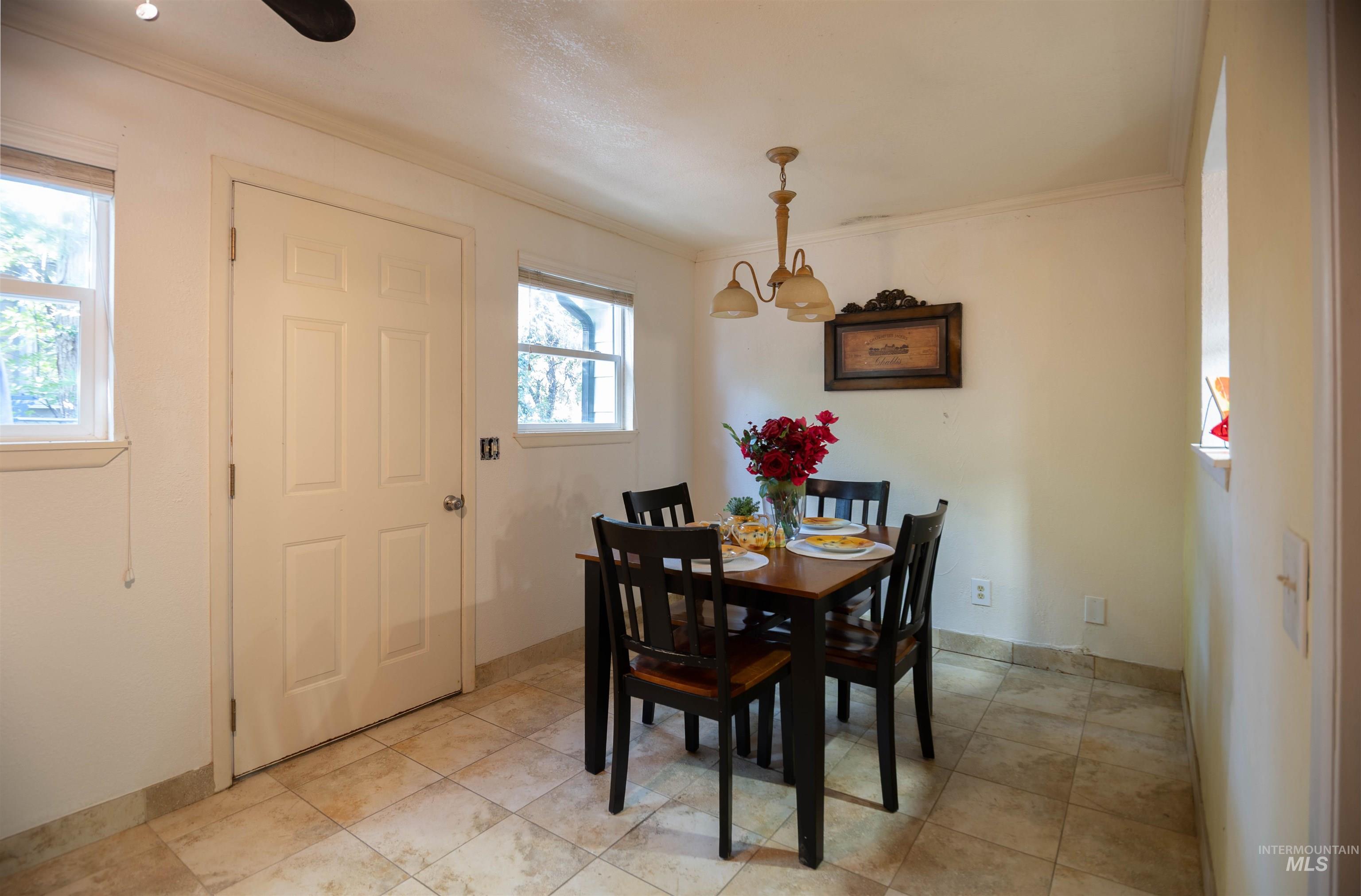 Dining room featuring ornamental molding, light tile patterned floors, and a chandelier