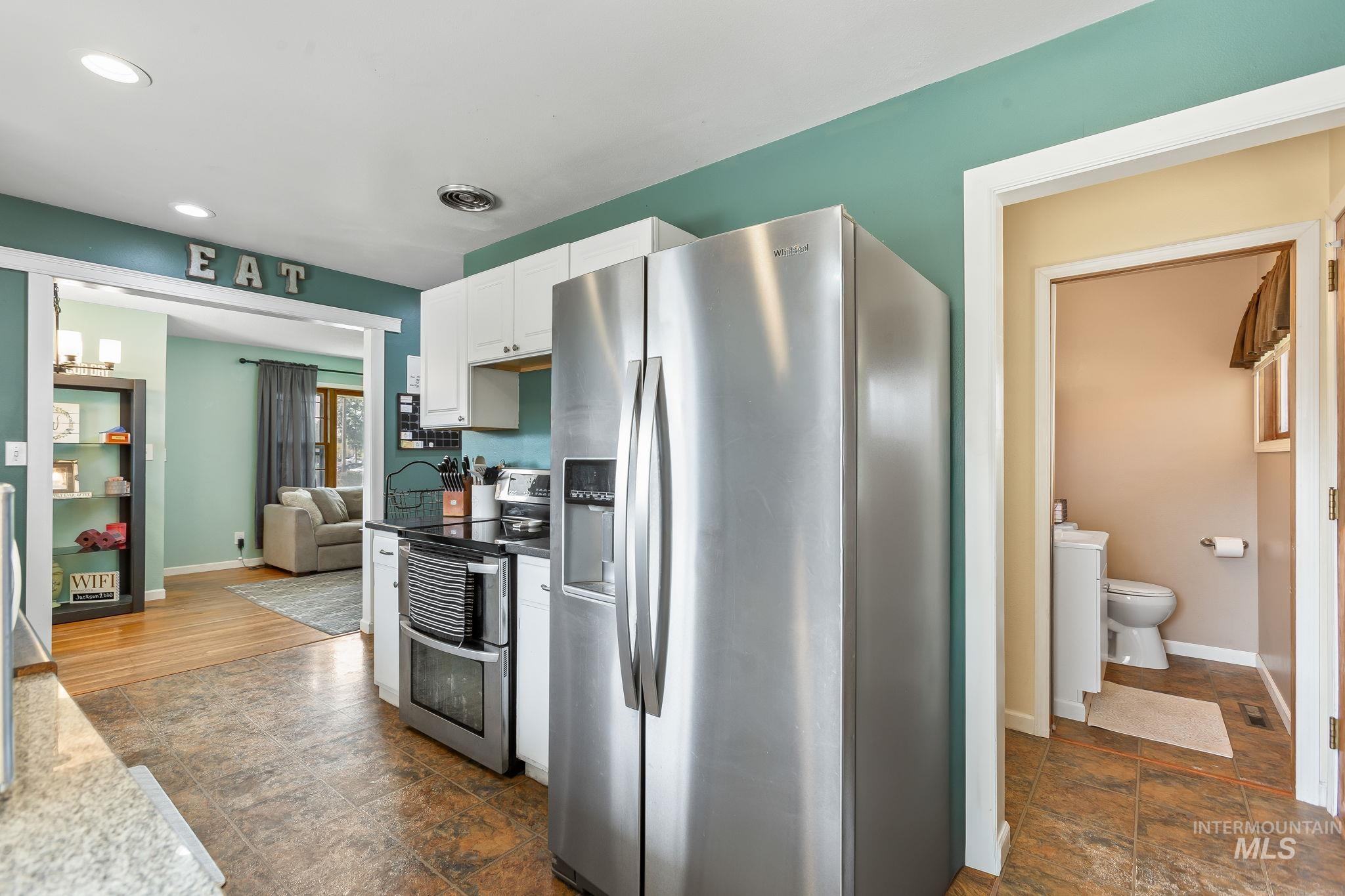 Kitchen with appliances with stainless steel finishes, white cabinets, recessed lighting, and stone finish floors