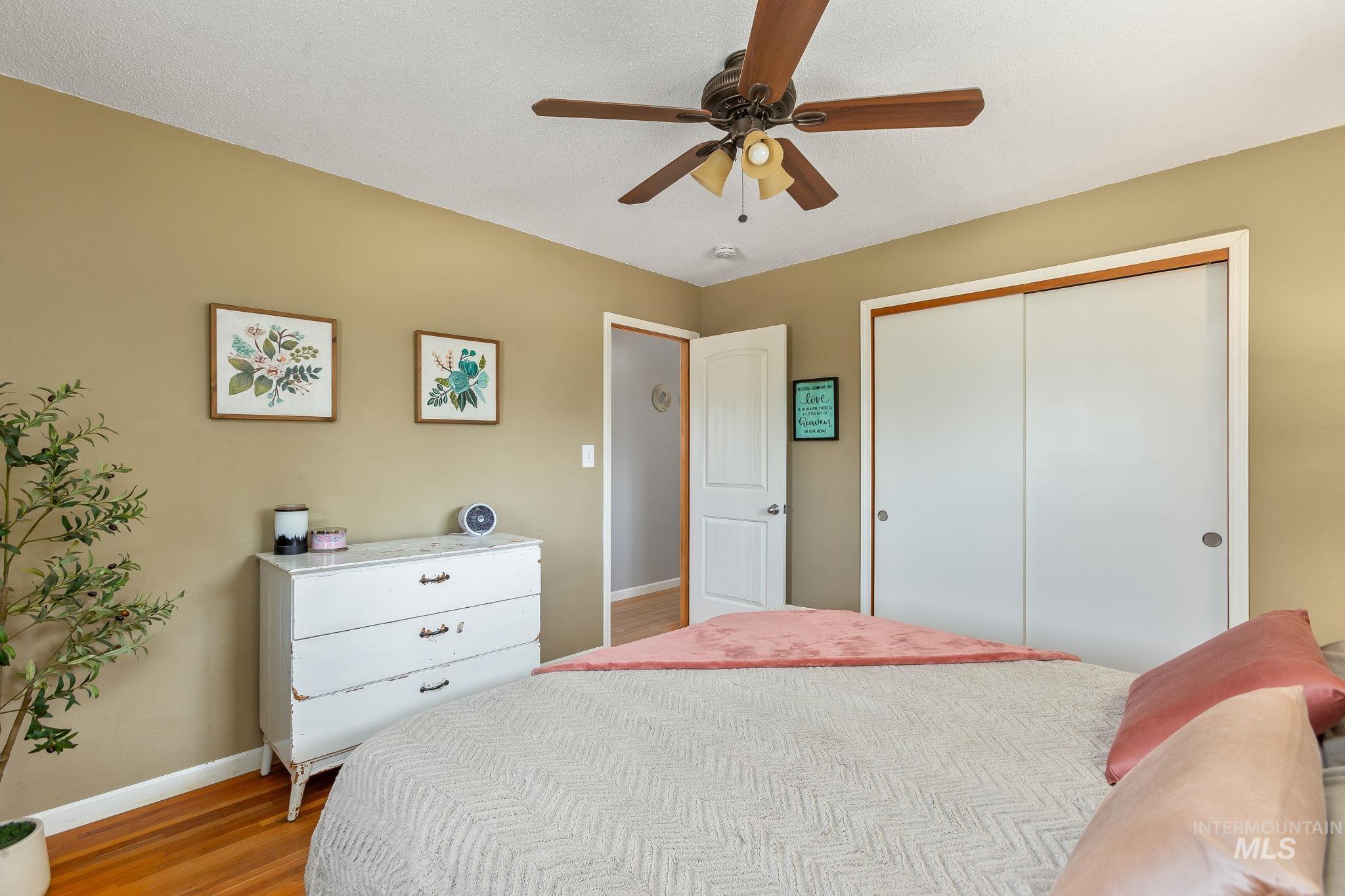 Bedroom with wood finished floors, a closet, and a ceiling fan