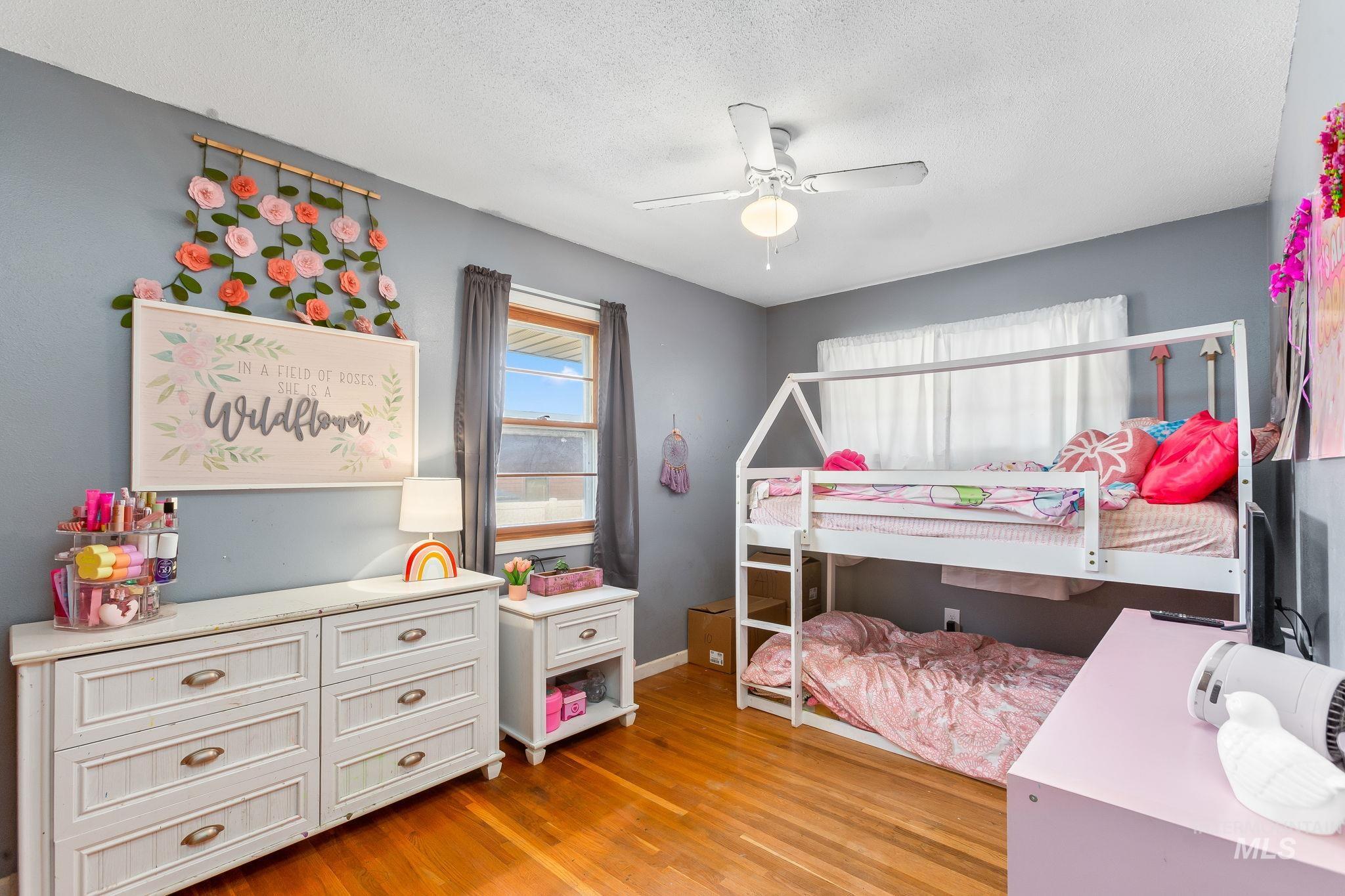 Bedroom featuring light wood-style flooring, a textured ceiling, and a ceiling fan