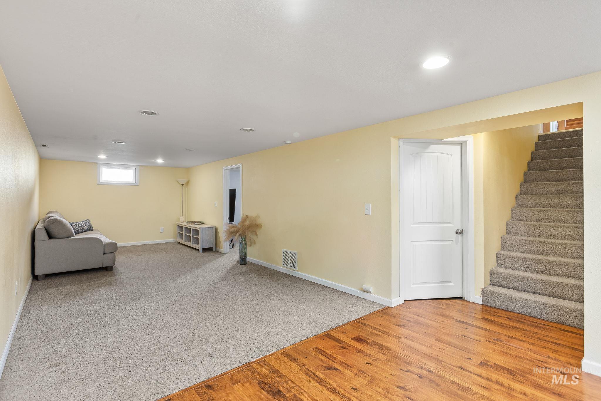 Unfurnished room with light wood-style floors, stairs, recessed lighting, and light colored carpet