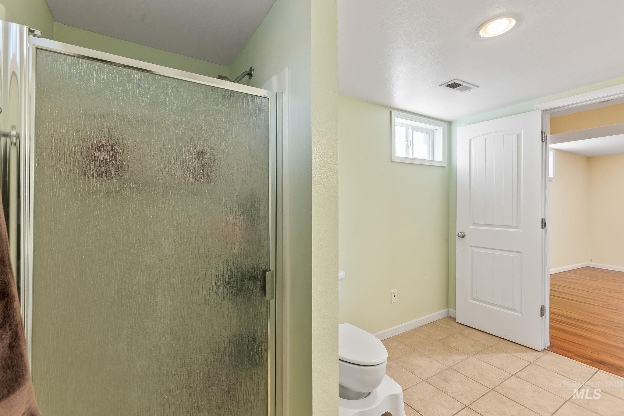 Full bath with a shower stall and light tile patterned flooring