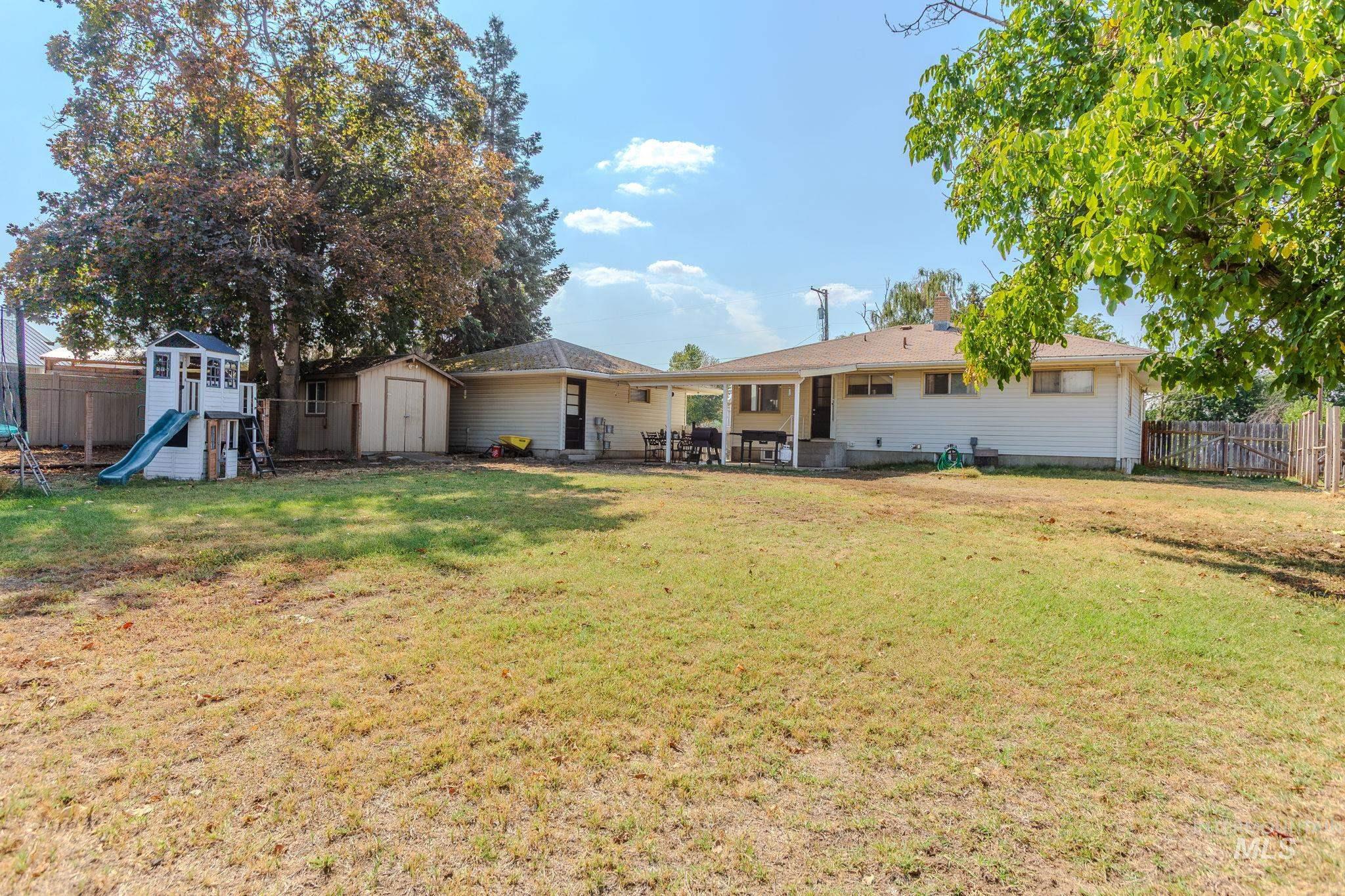 Back of house with a storage unit and a patio