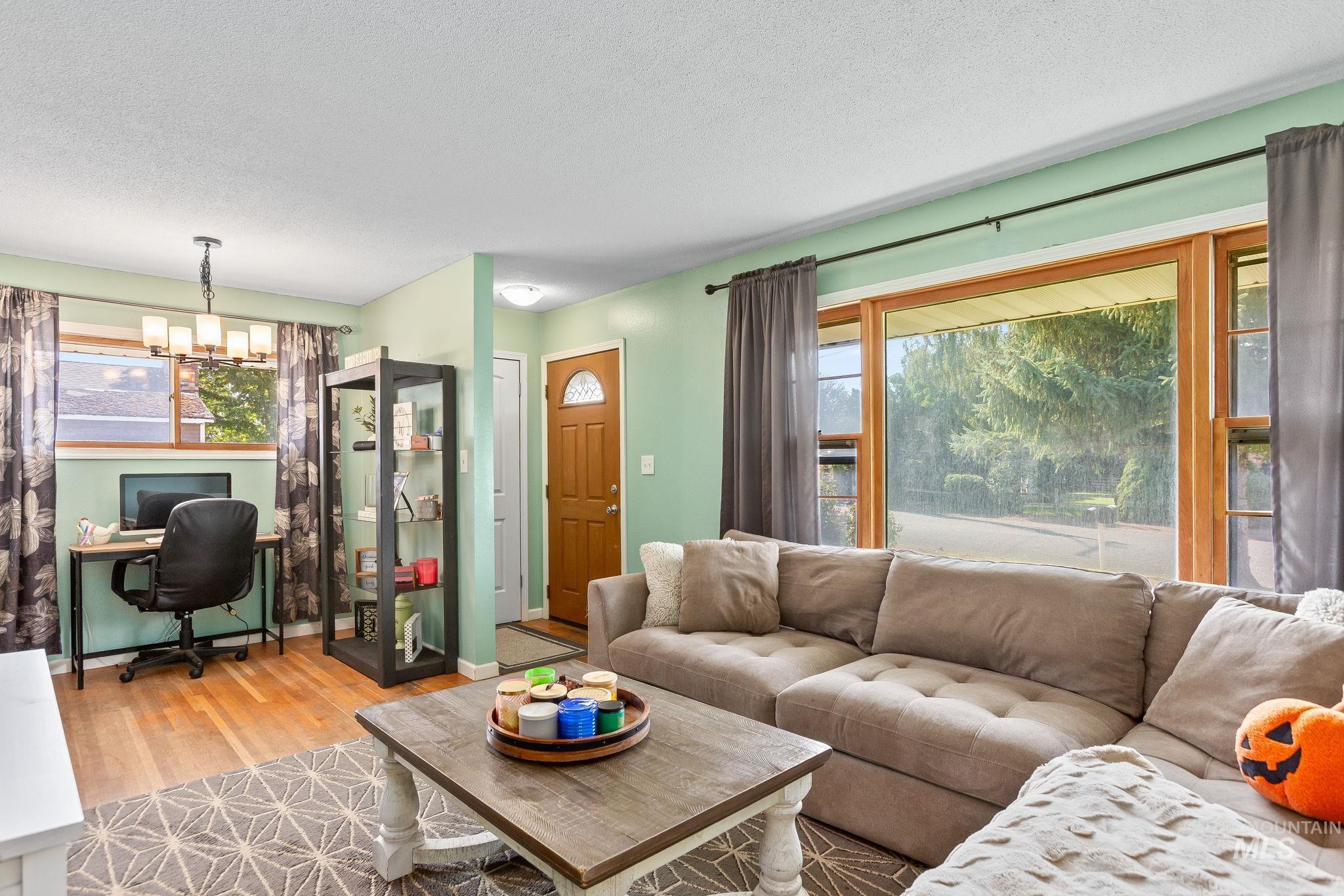 Living area featuring a desk, wood finished floors, a textured ceiling, and a chandelier