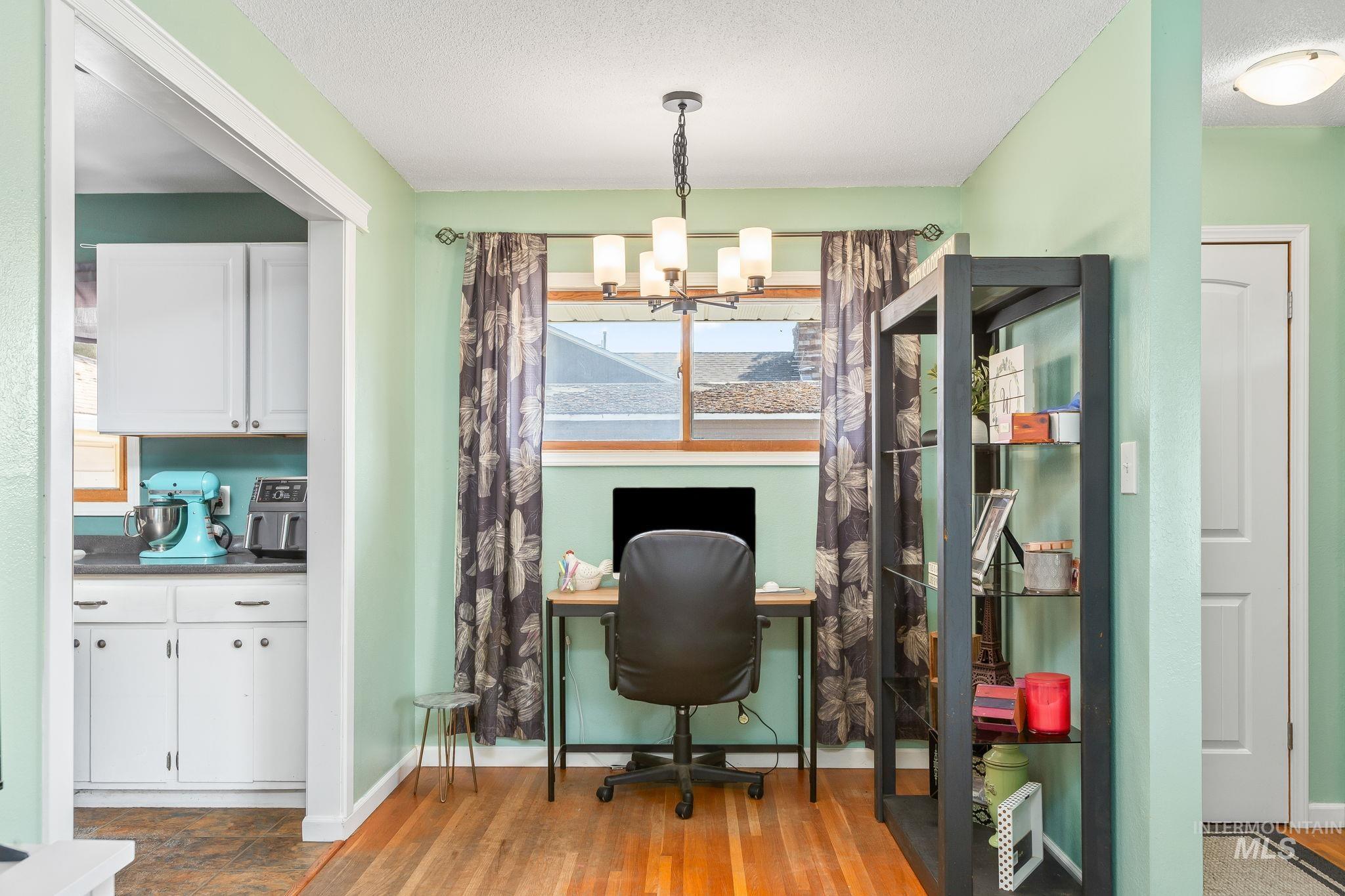 Home office featuring a chandelier, light wood-style flooring, and a textured ceiling