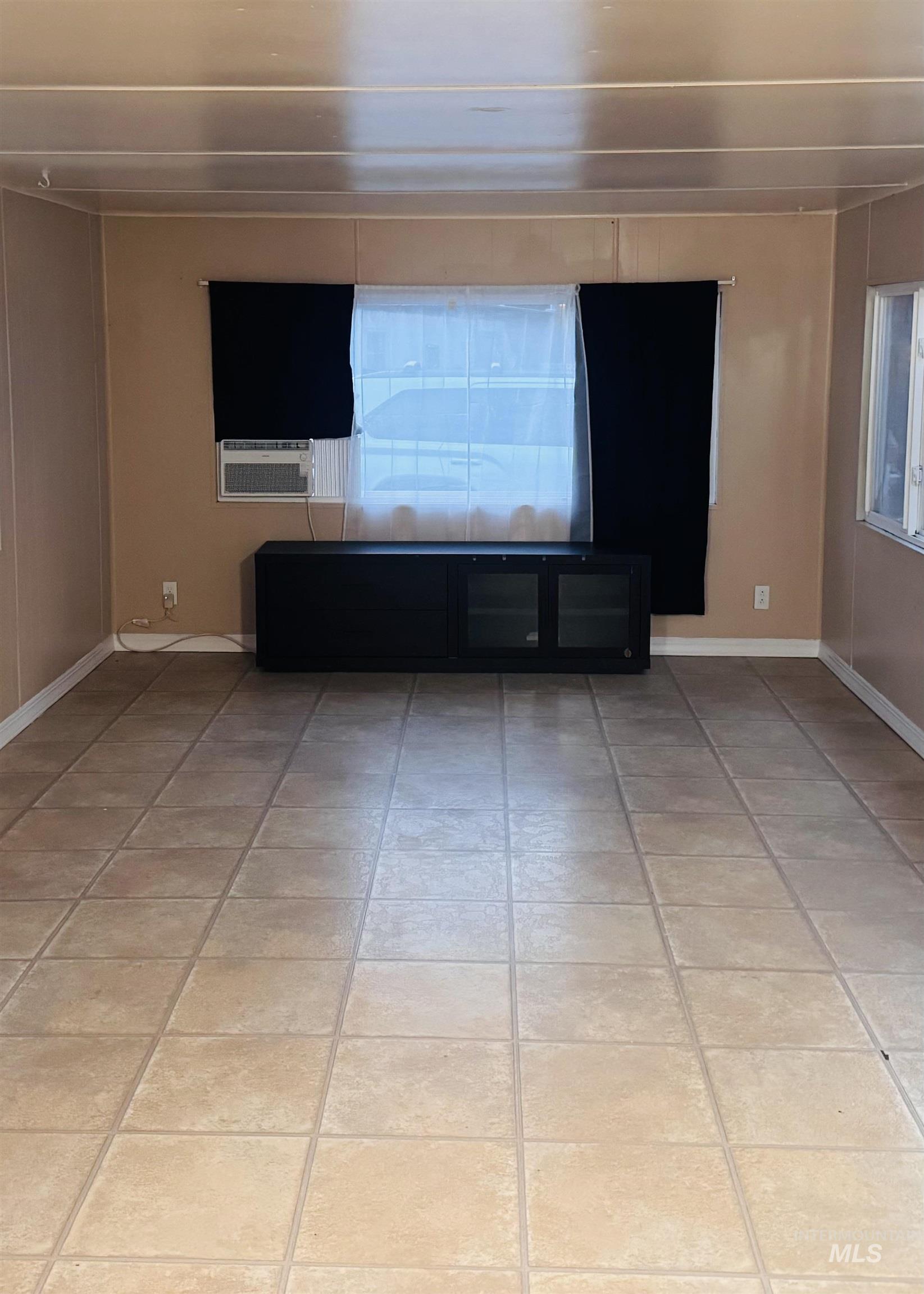 Unfurnished living room featuring light tile patterned floors and cooling unit