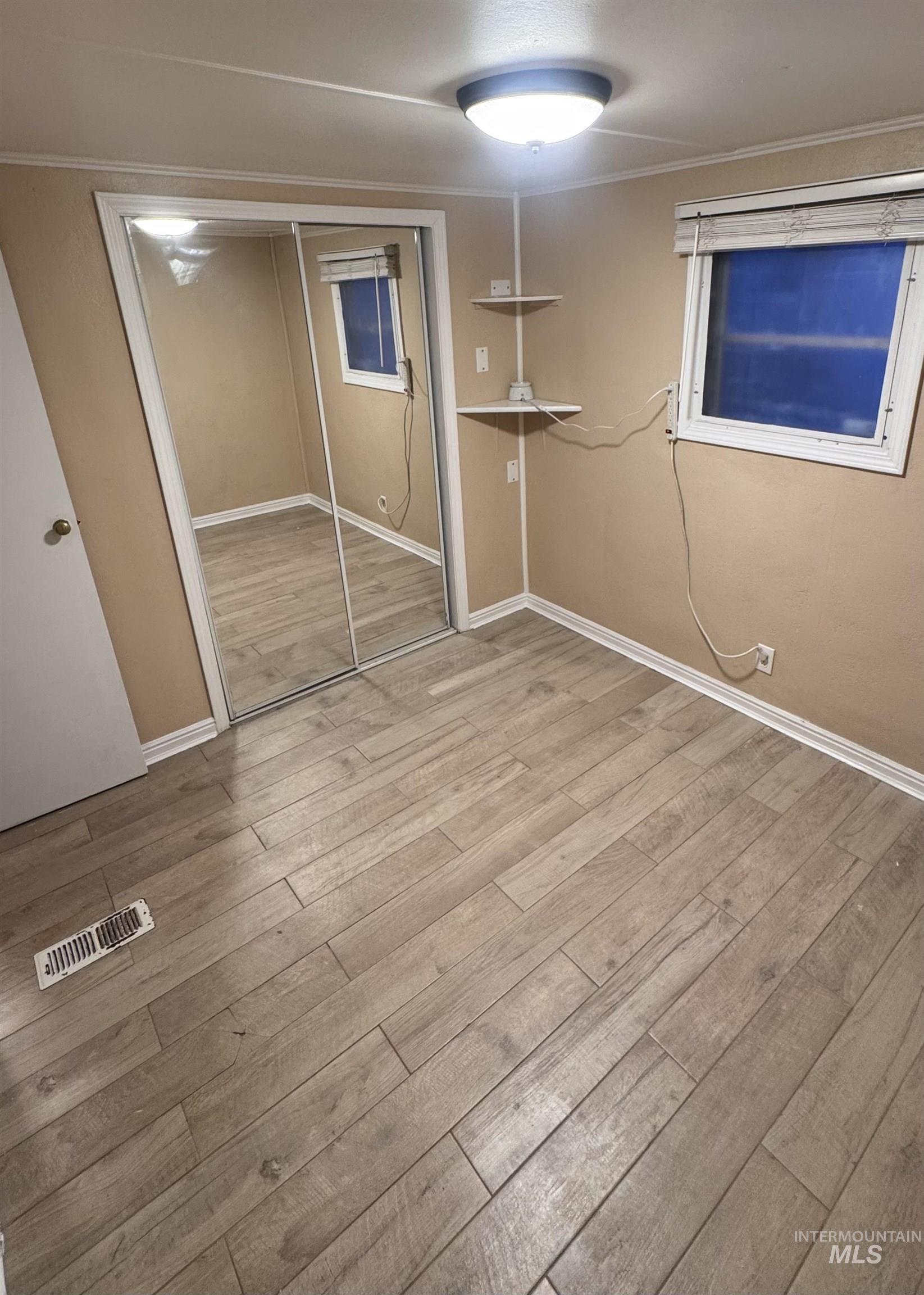 Unfurnished bedroom featuring a closet, ornamental molding, and light wood finished floors