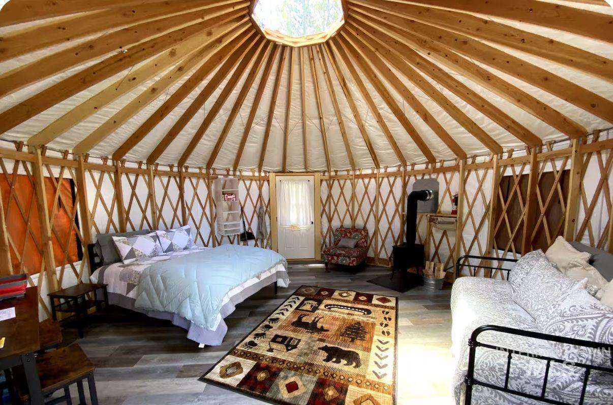 Unfurnished bedroom featuring a wood stove, wood finished floors, and vaulted ceiling