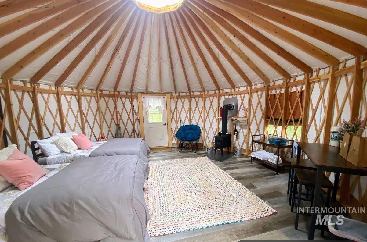 Bedroom featuring a wood stove, vaulted ceiling, and wood finished floors