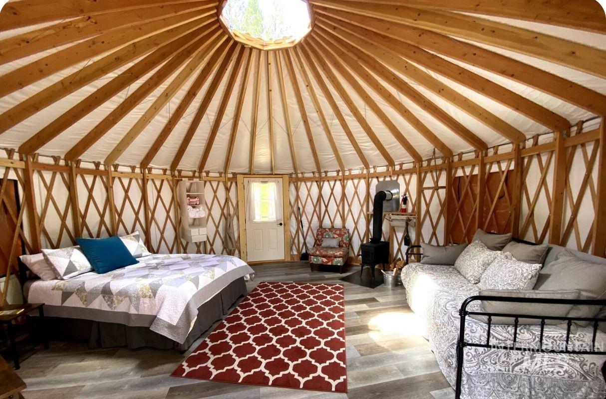 Bedroom featuring a wood stove, vaulted ceiling, and wood finished floors