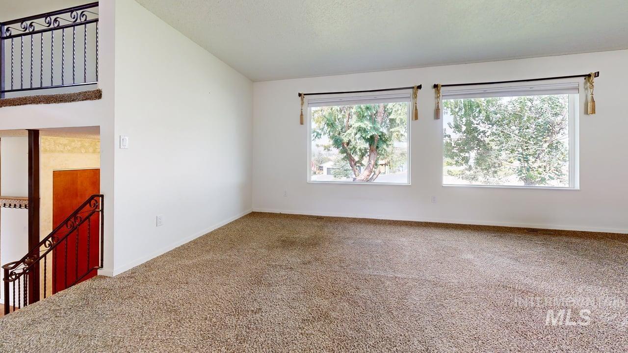 Carpeted spare room featuring lofted ceiling and baseboards