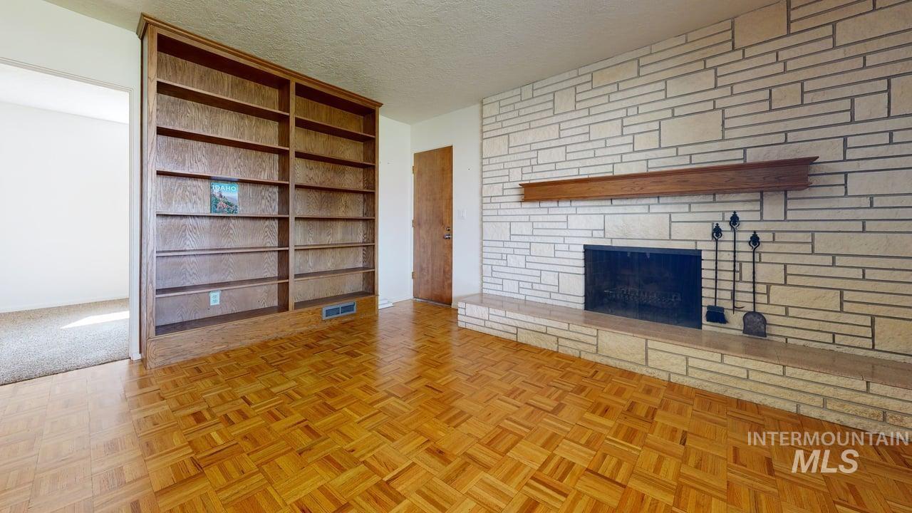 Unfurnished living room featuring a textured ceiling, a fireplace, and built in shelves