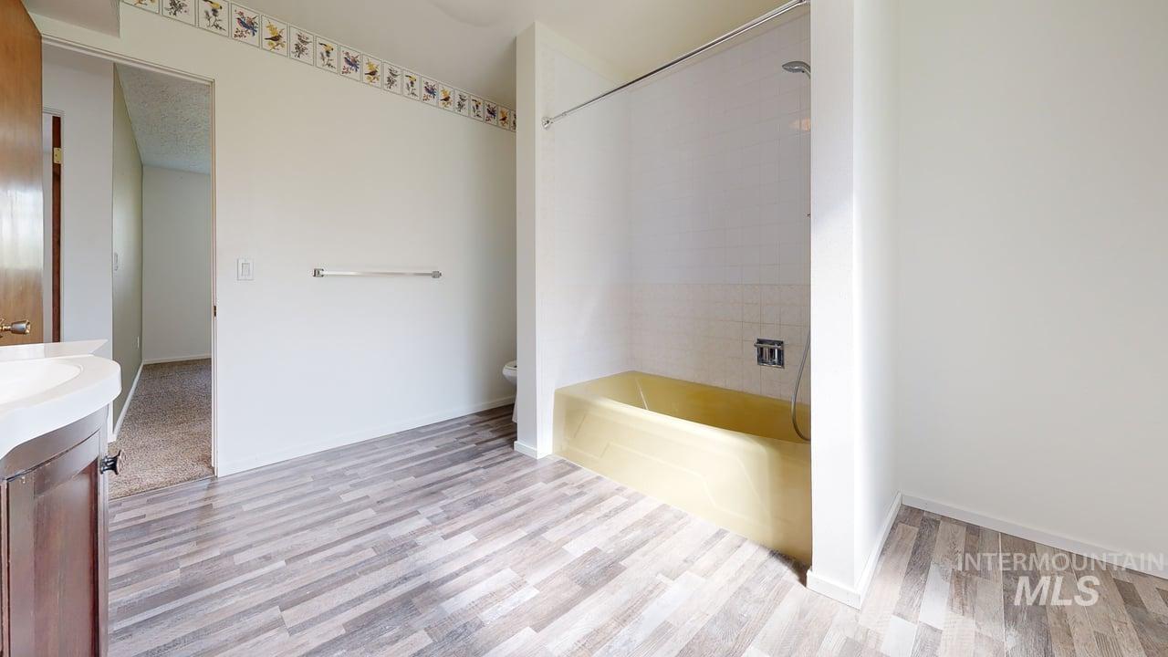 Bathroom with vanity, bathing tub / shower combination, and light wood-style flooring