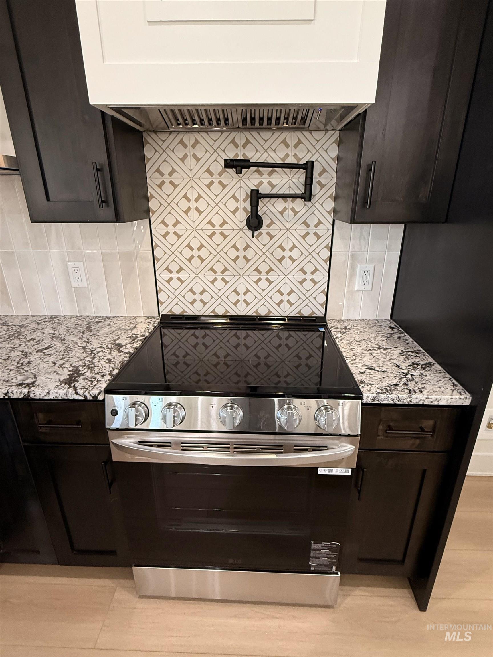 Kitchen featuring backsplash, electric stove, dark brown cabinets, and custom exhaust hood
