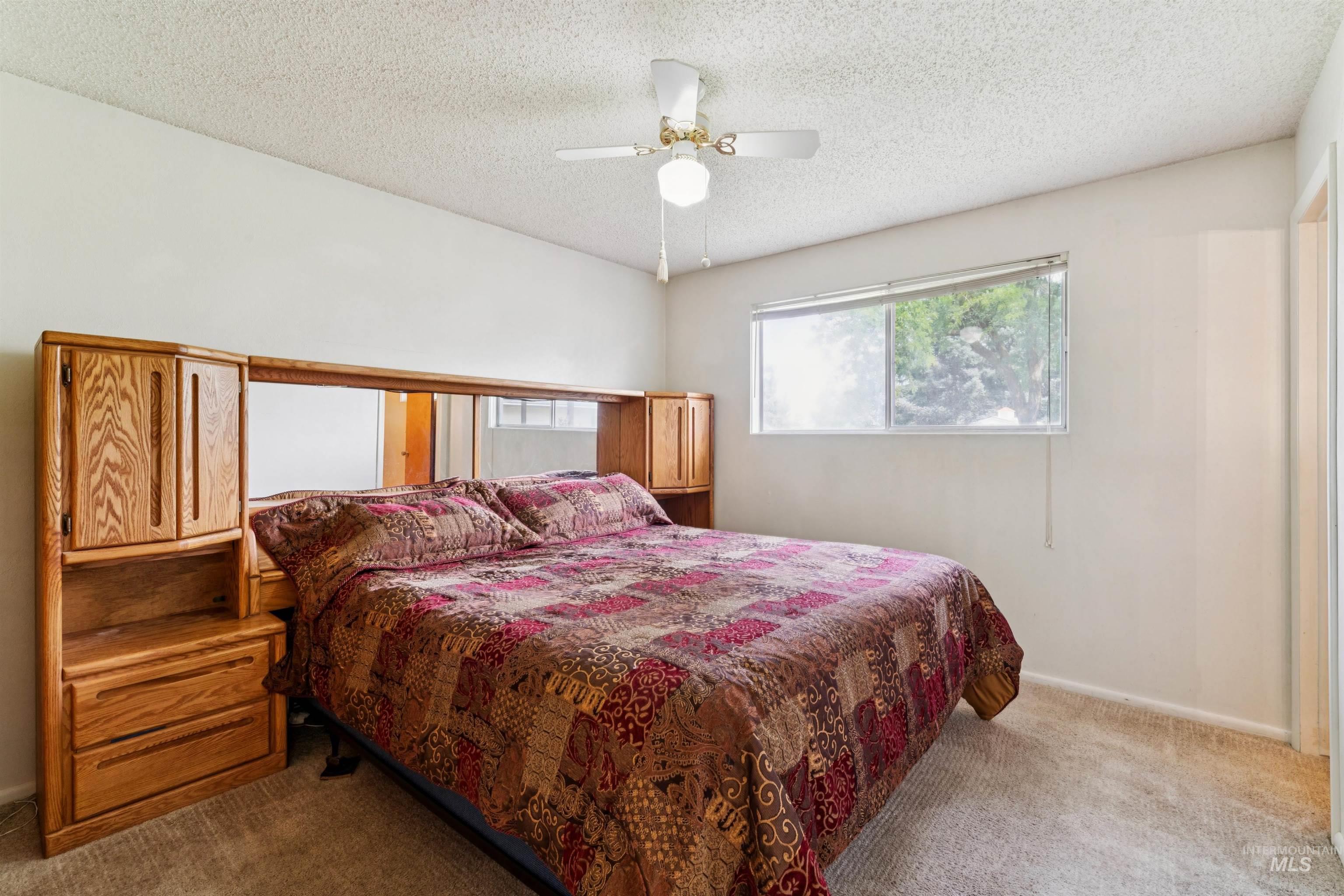 Bedroom with carpet floors, ceiling fan, and a textured ceiling