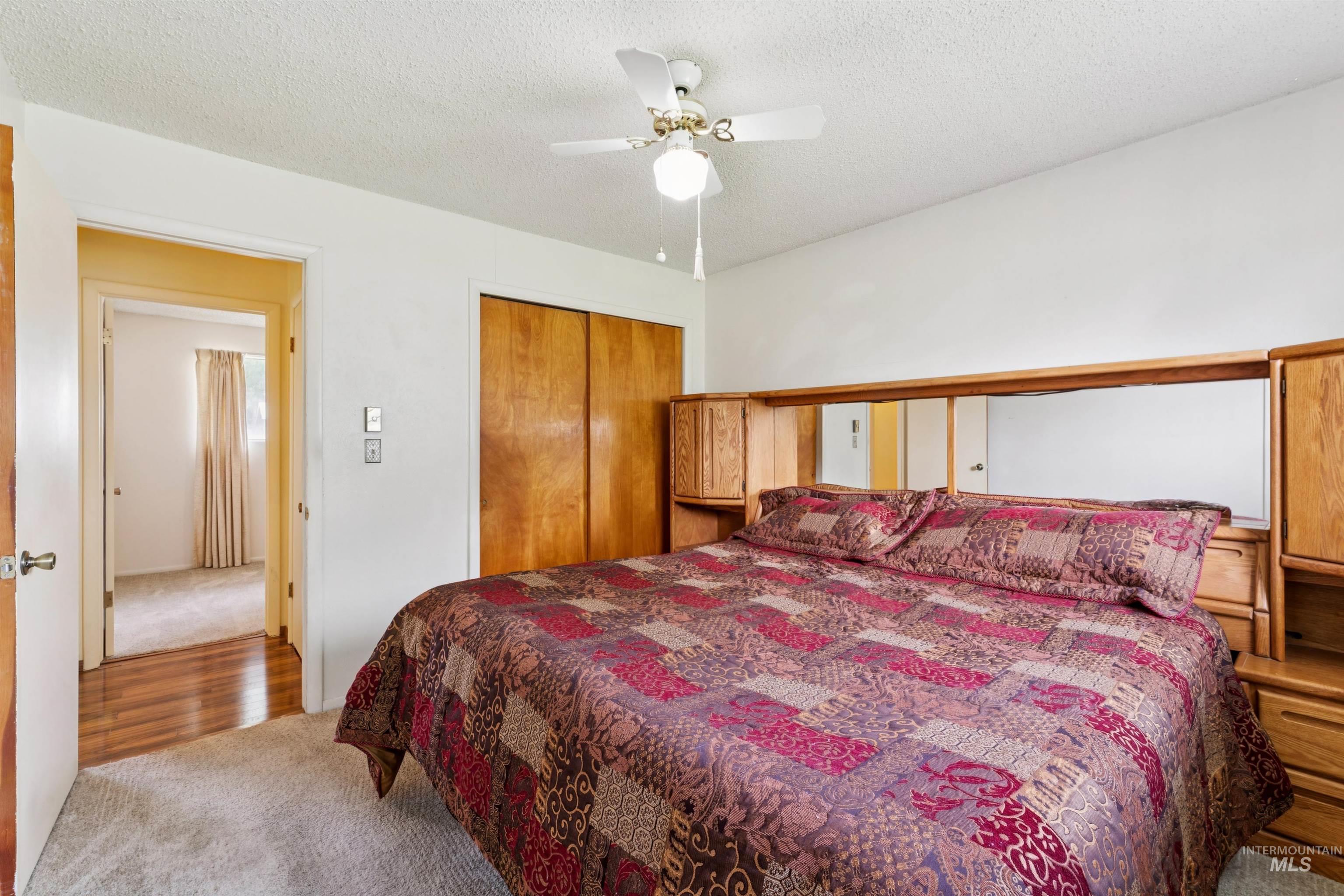 Bedroom with carpet floors, a textured ceiling, a ceiling fan, and a closet