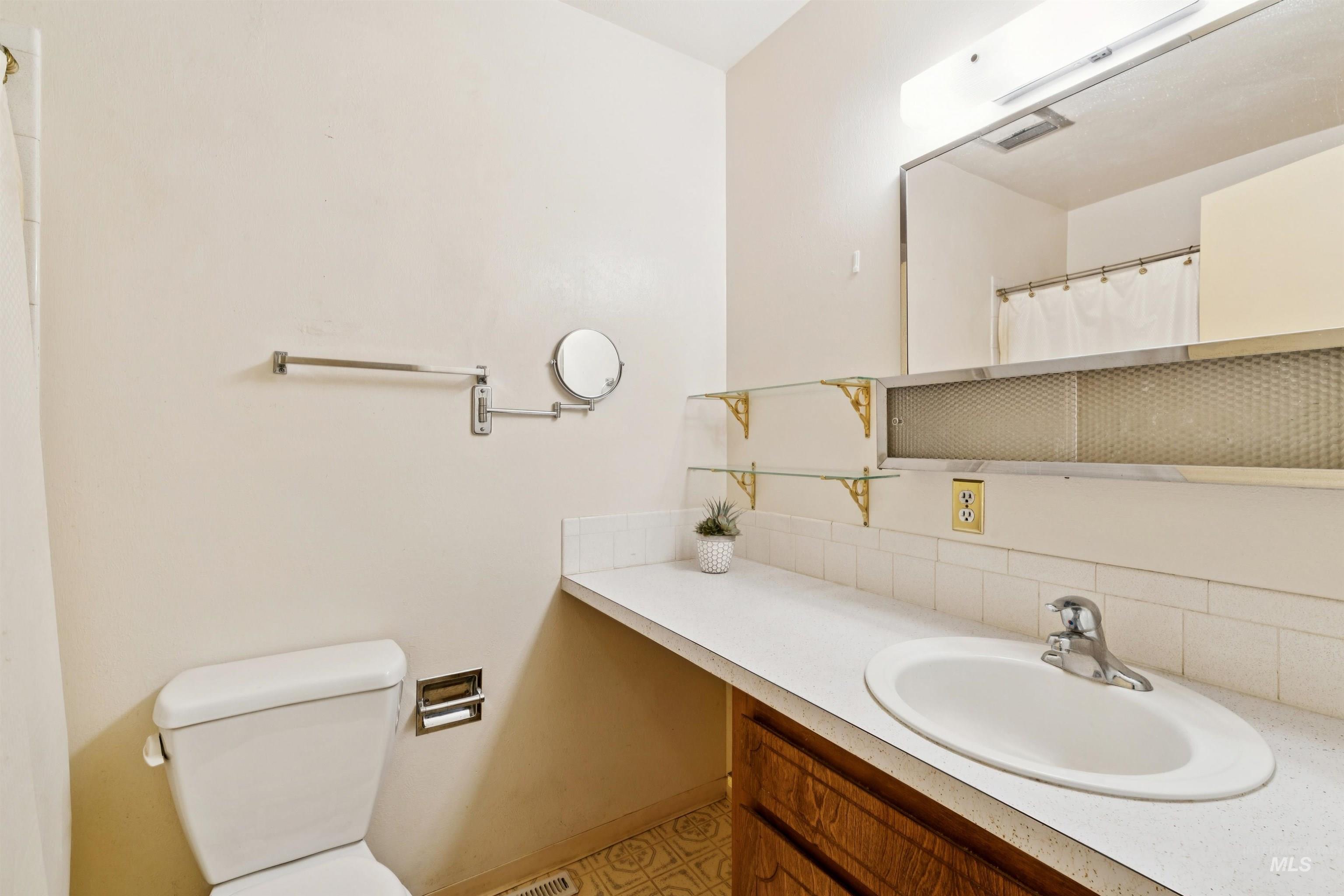 Full bathroom featuring vanity, curtained shower, and tasteful backsplash