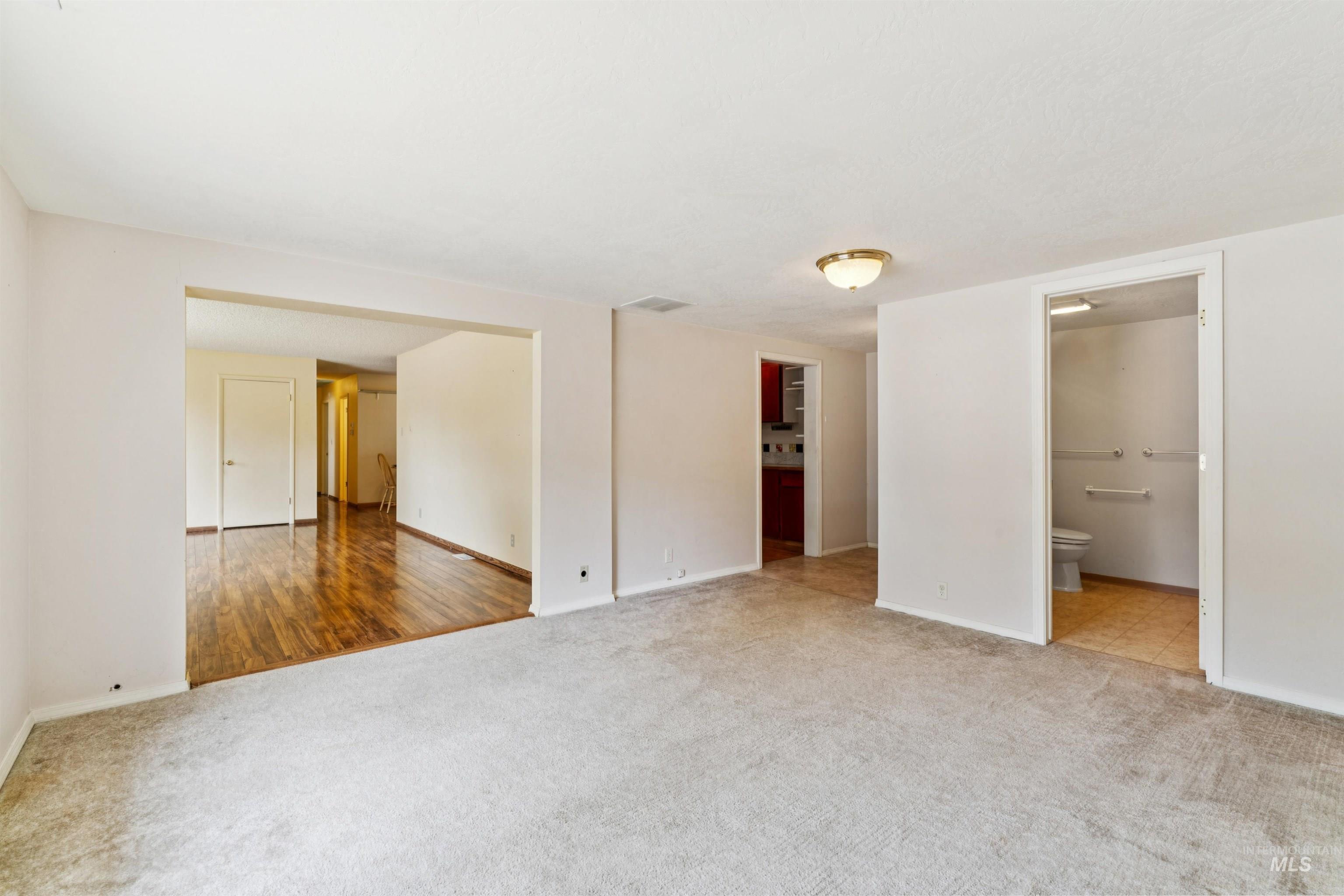 Unfurnished bedroom with light carpet and ensuite bath