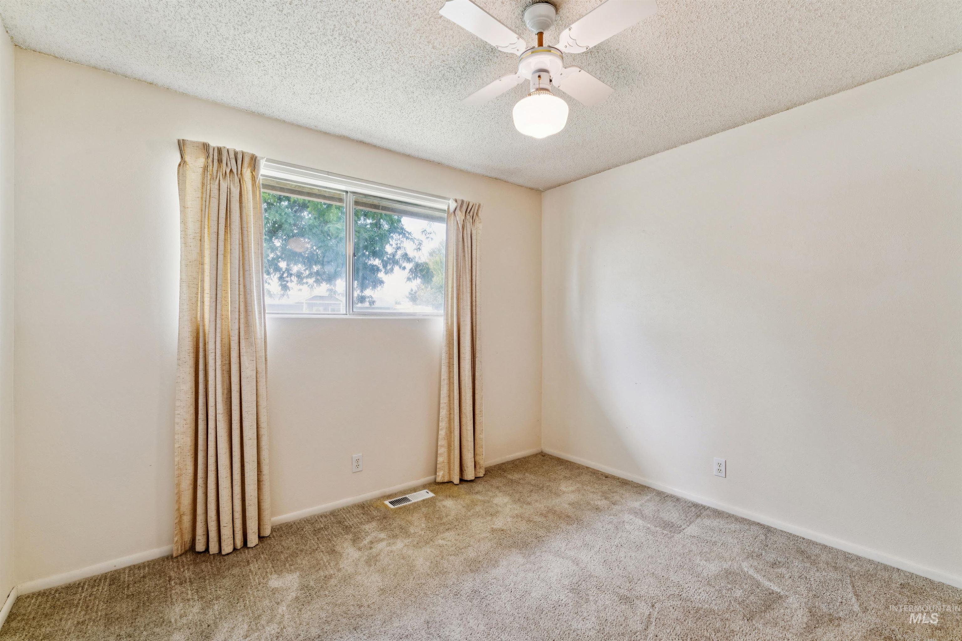 Carpeted spare room with a textured ceiling and ceiling fan