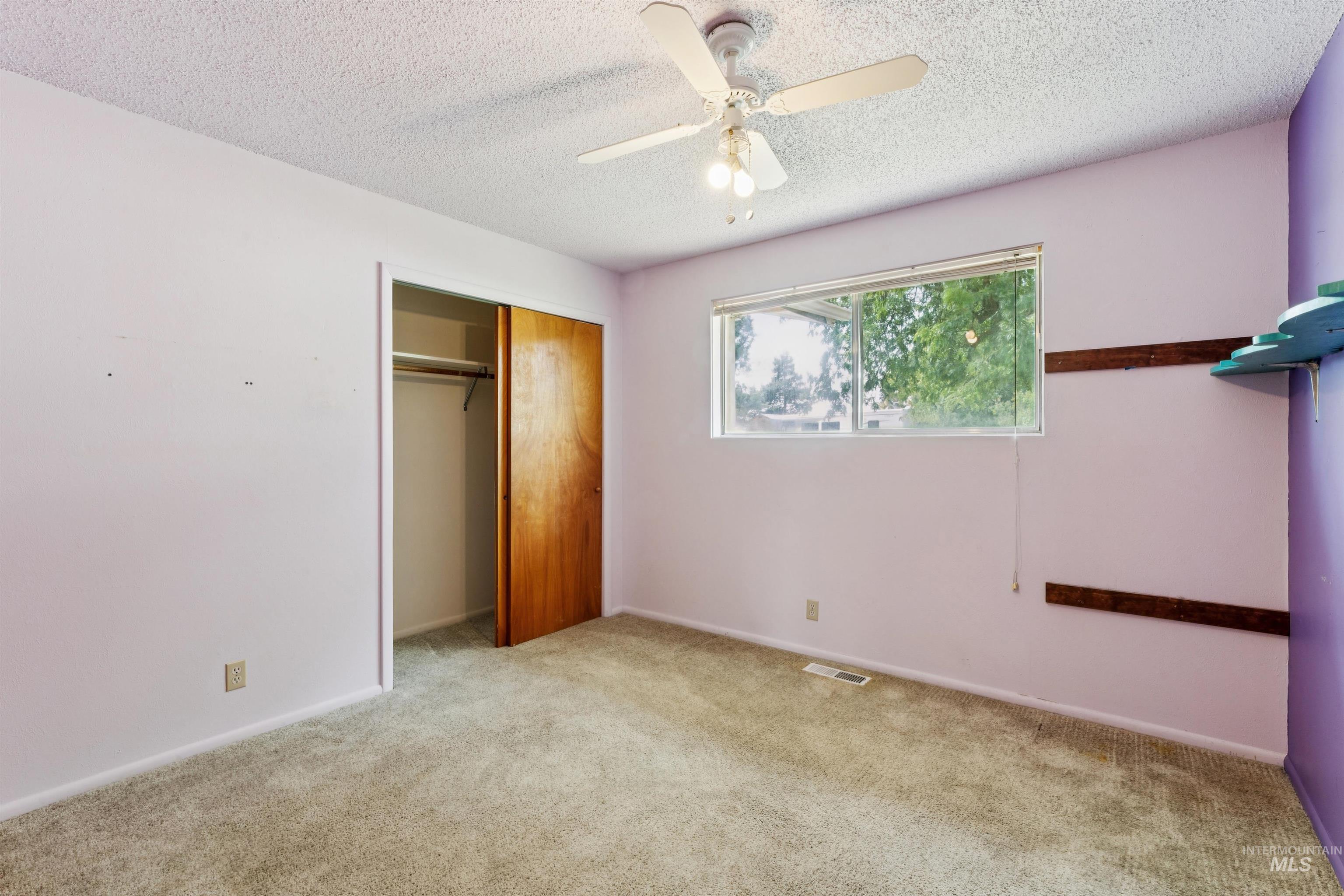 Unfurnished bedroom featuring light carpet, a ceiling fan, a closet, and a textured ceiling