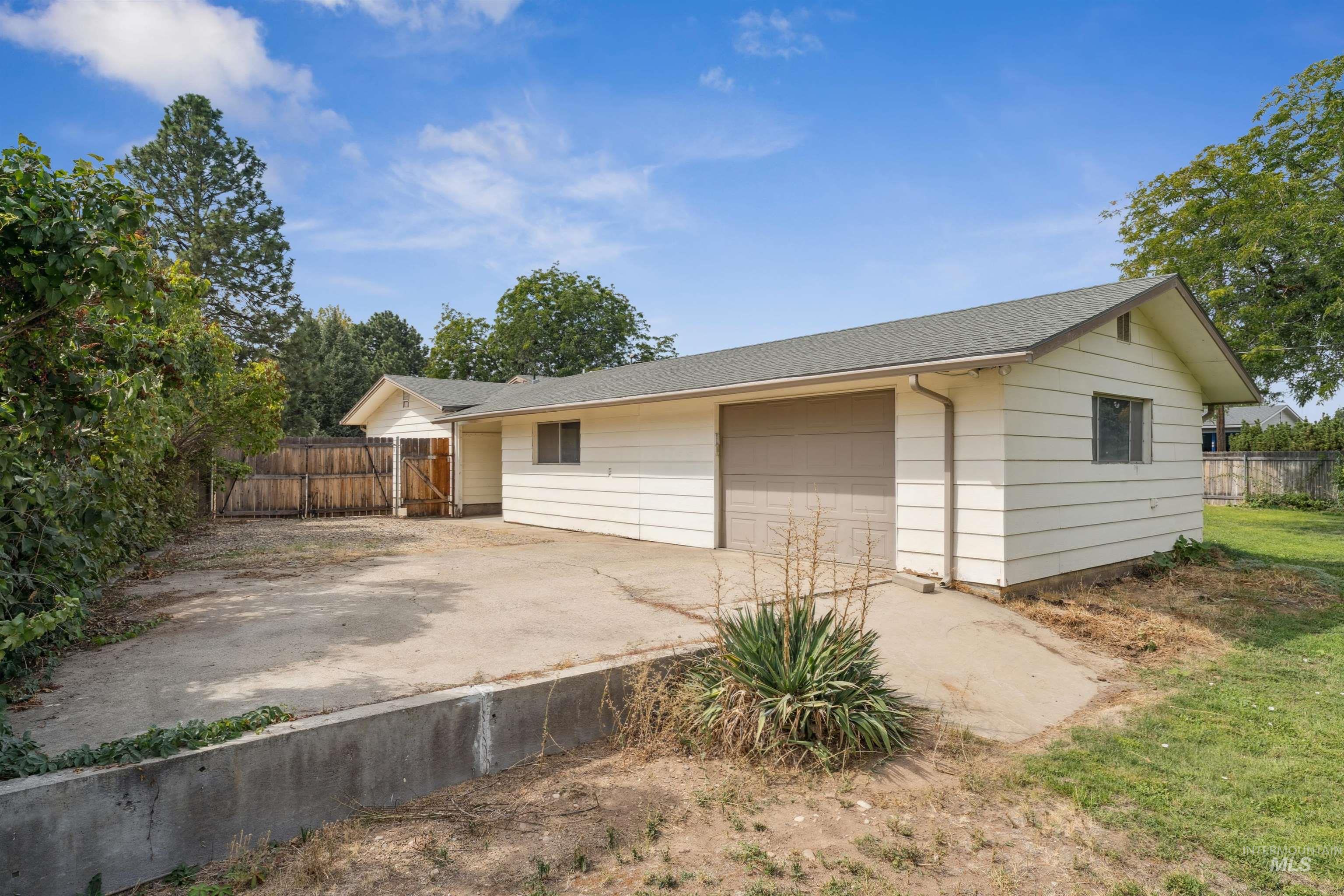 View of front of home featuring a shingled roof, a garage, and driveway