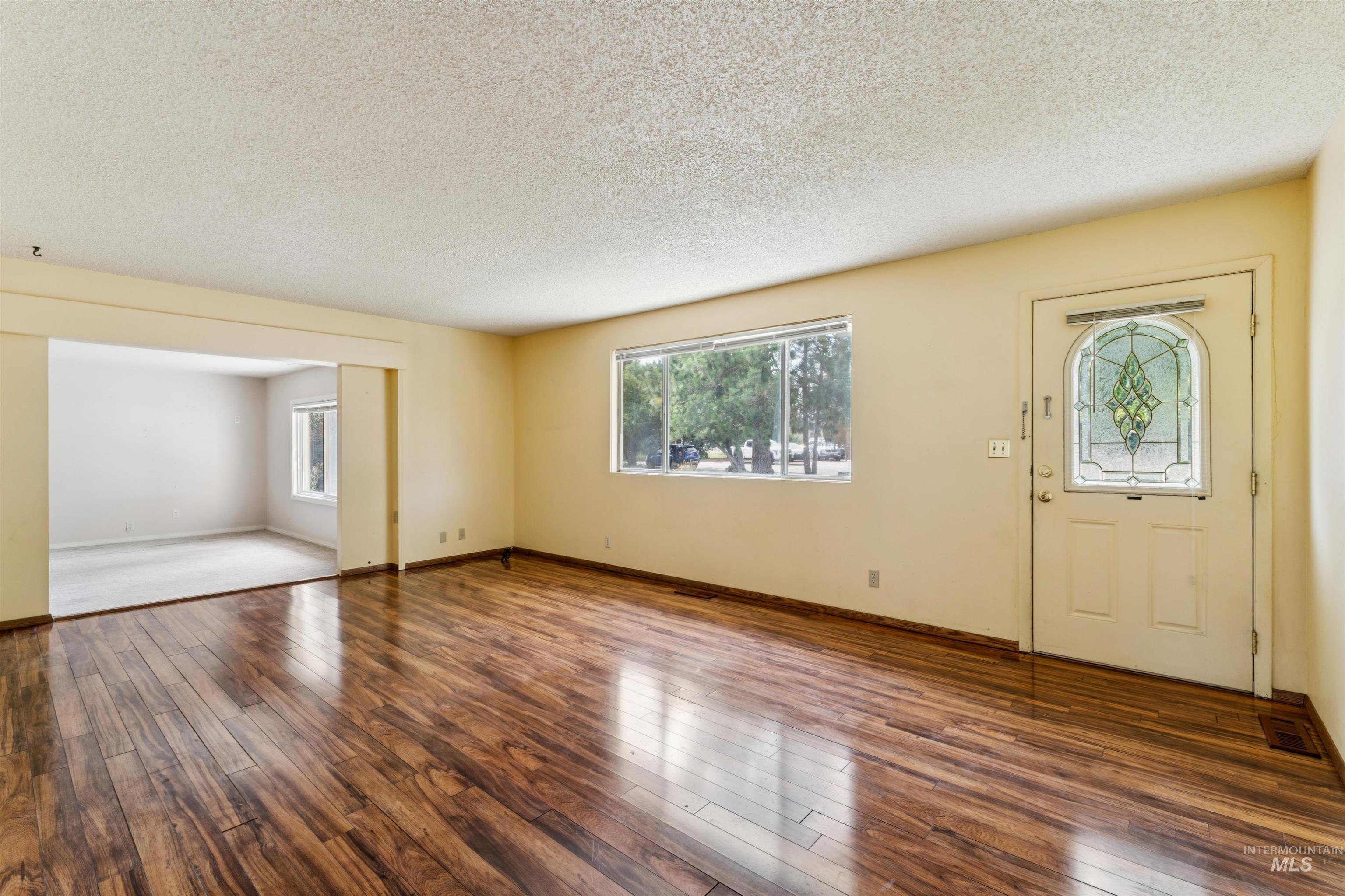 Foyer entrance featuring plenty of natural light, dark wood-style flooring, and a textured ceiling