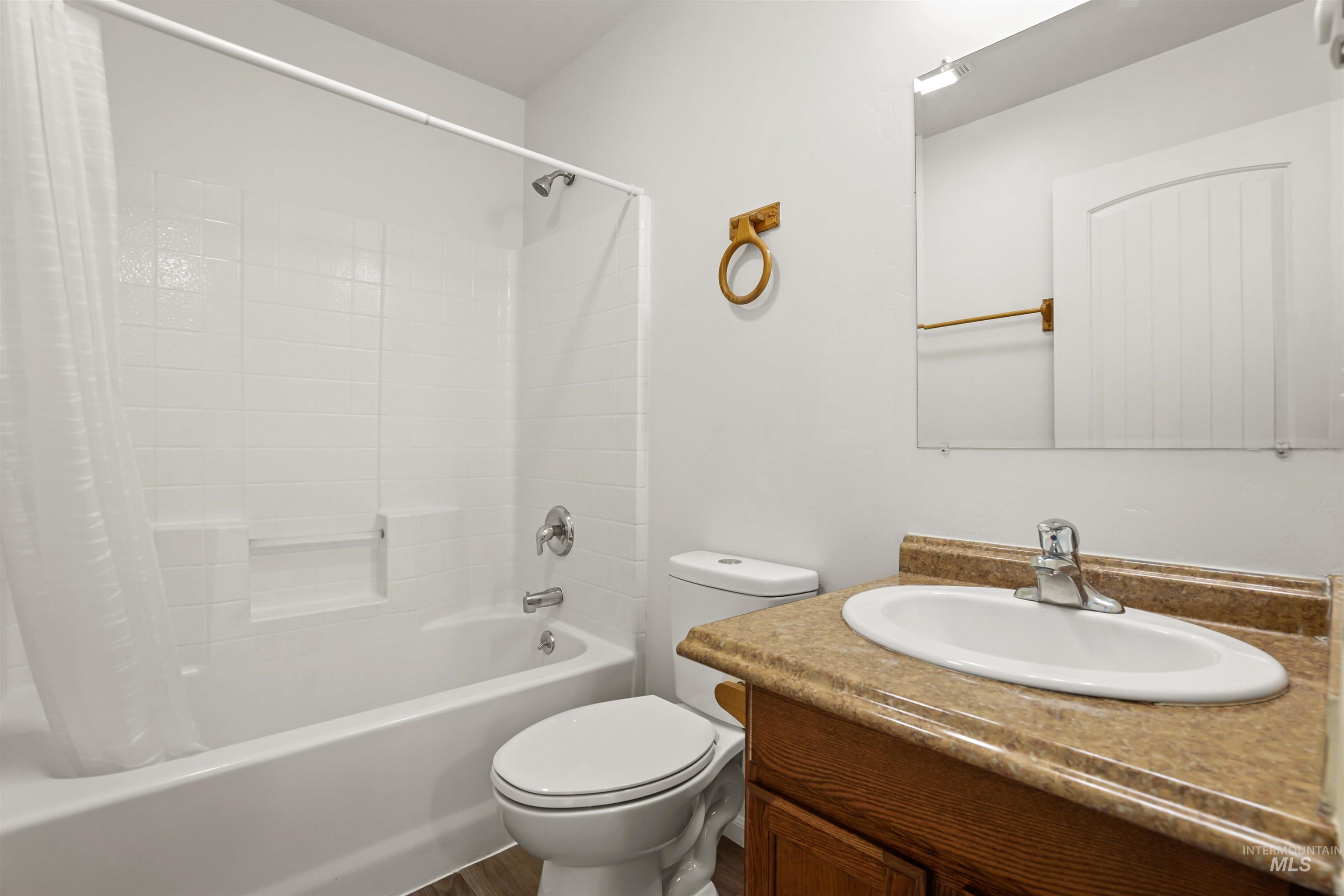 Full bathroom with shower / tub combo, vanity, and dark wood-style flooring