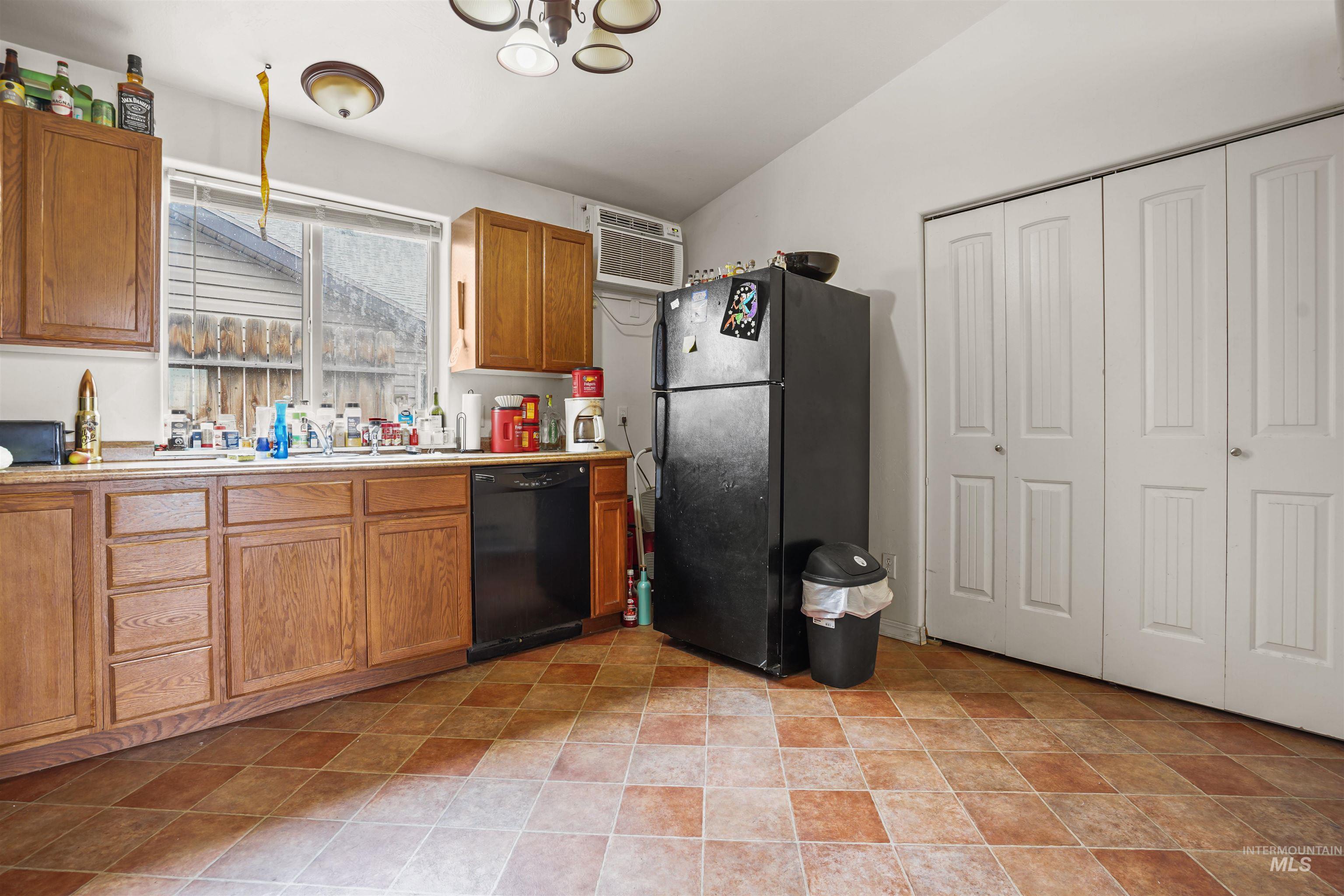 Kitchen with light countertops, black appliances, brown cabinetry, and a wall mounted air conditioner