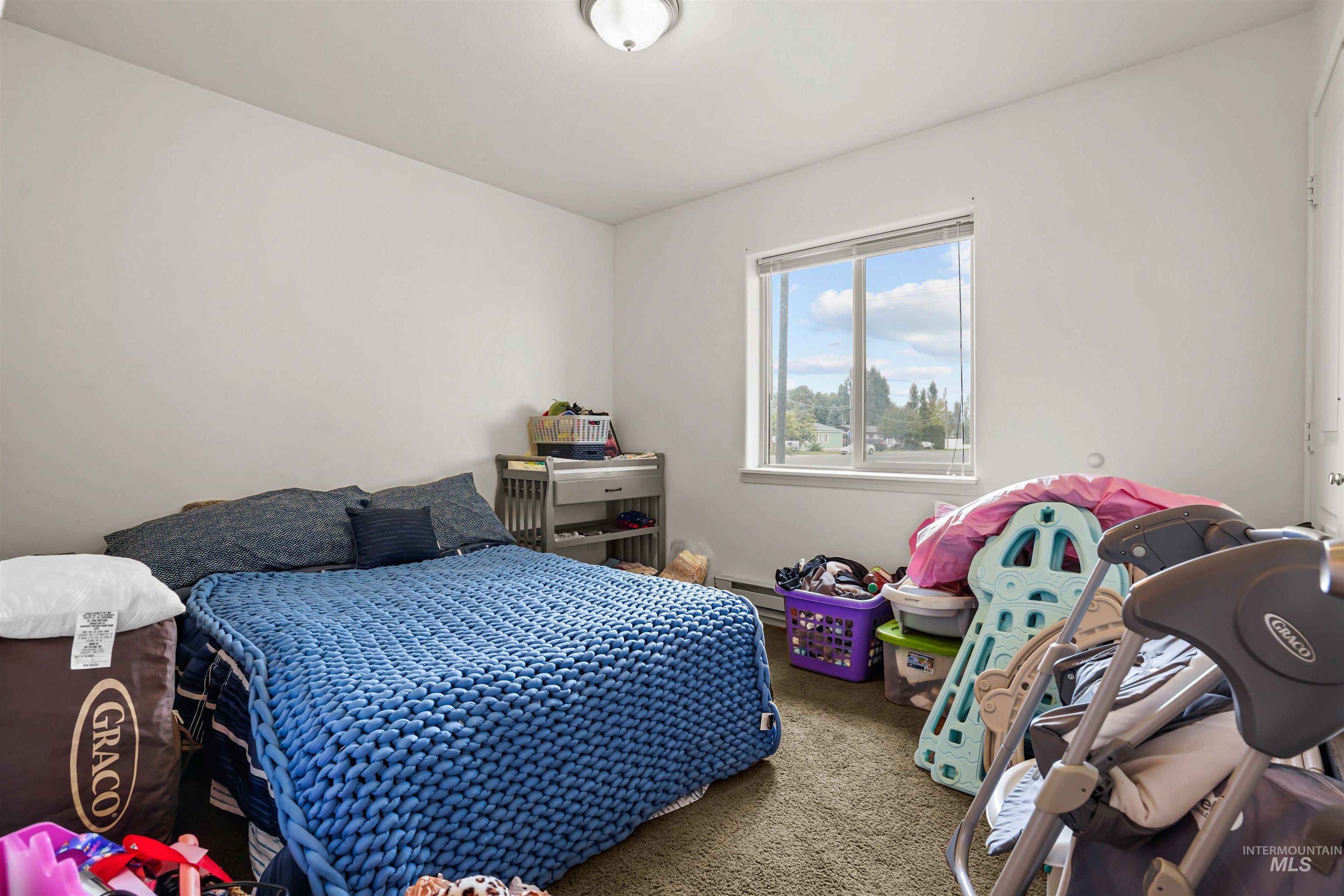 Bedroom with carpet flooring and a baseboard heating unit