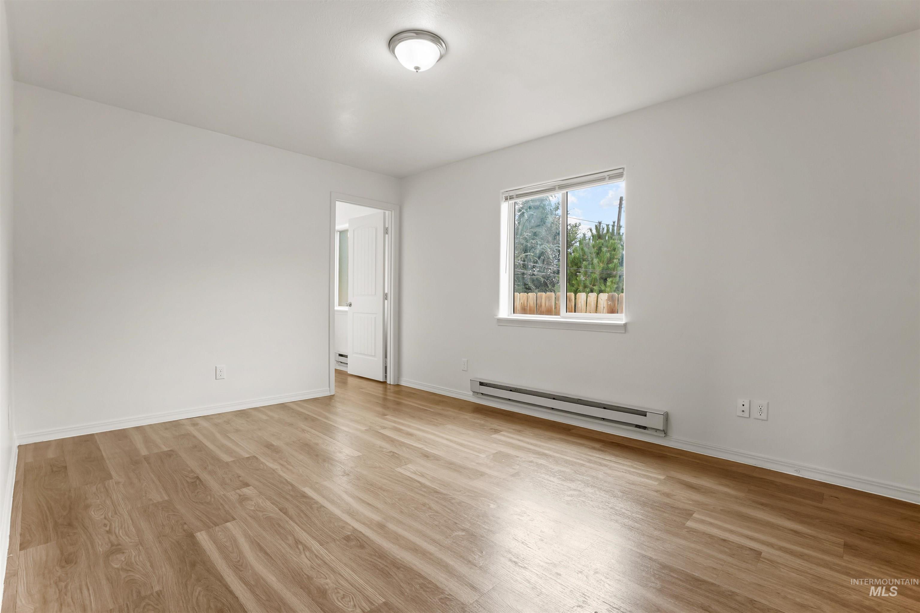 Empty room with a baseboard radiator and light wood-type flooring