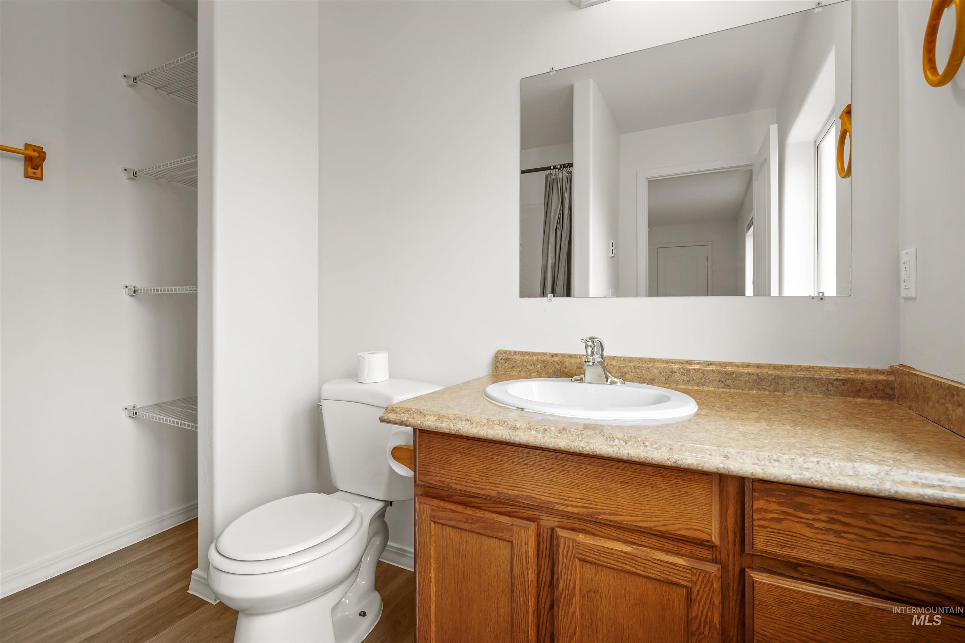 Bathroom with vanity, dark wood-style floors, and curtained shower