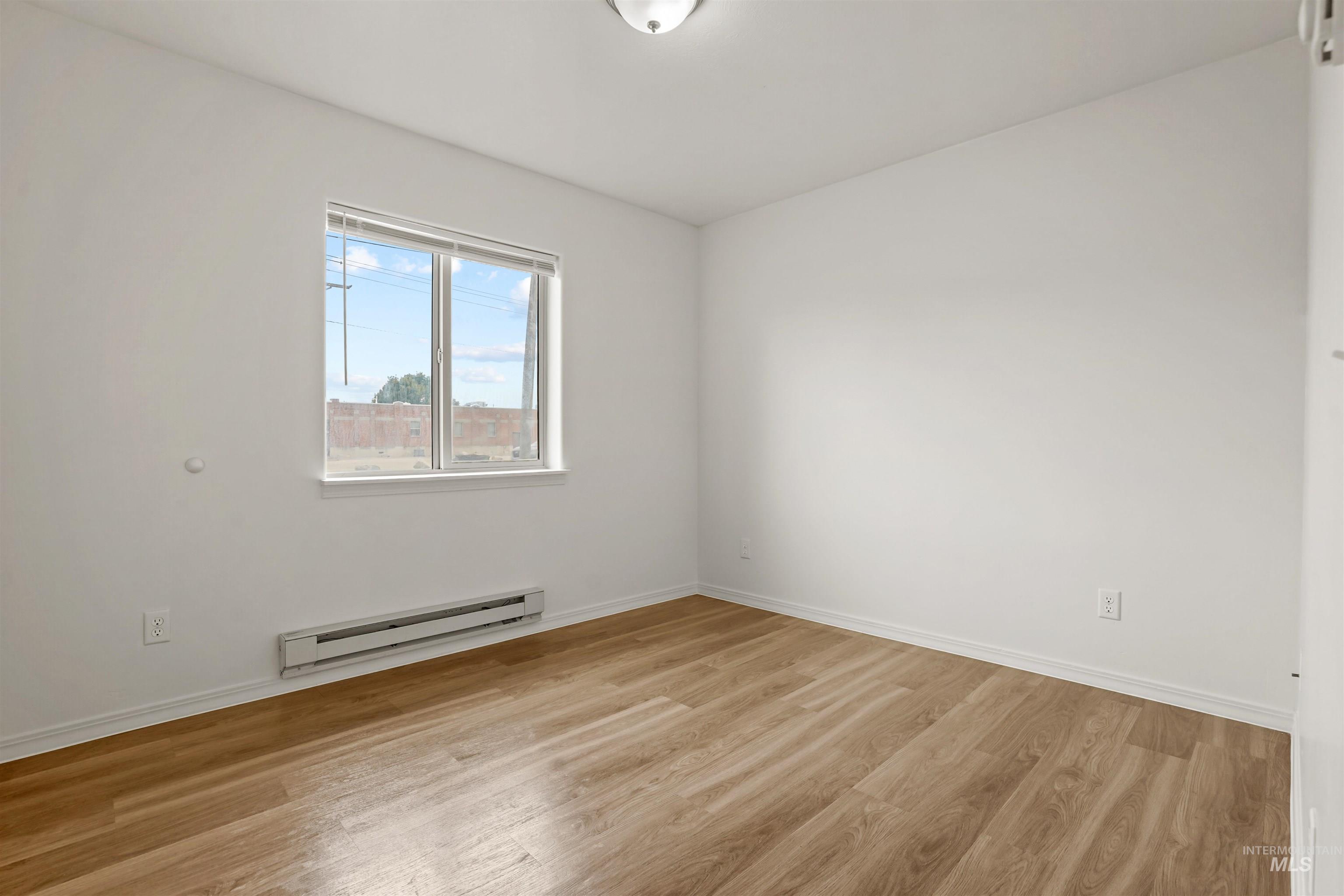 Spare room featuring a baseboard radiator and light wood-type flooring