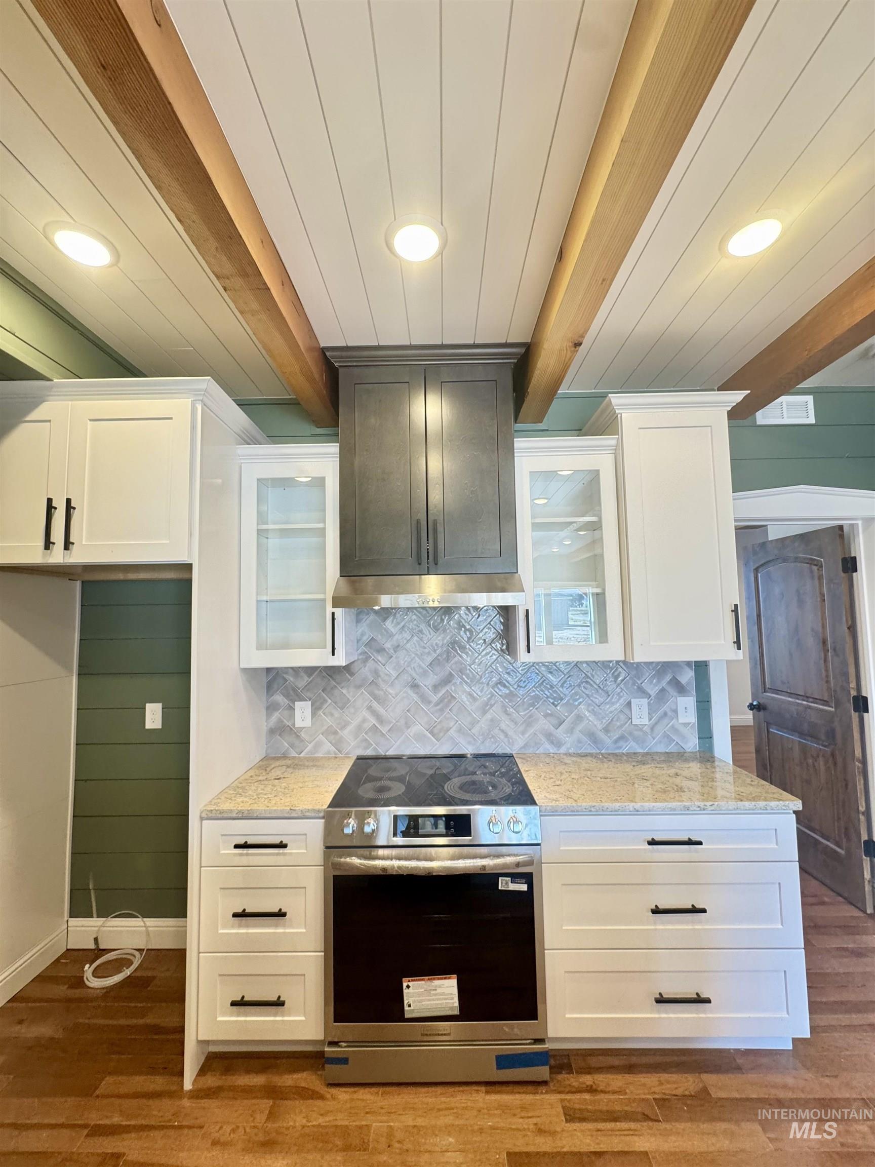Kitchen featuring glass insert cabinets, beamed ceiling, electric range, white cabinets, and recessed lighting