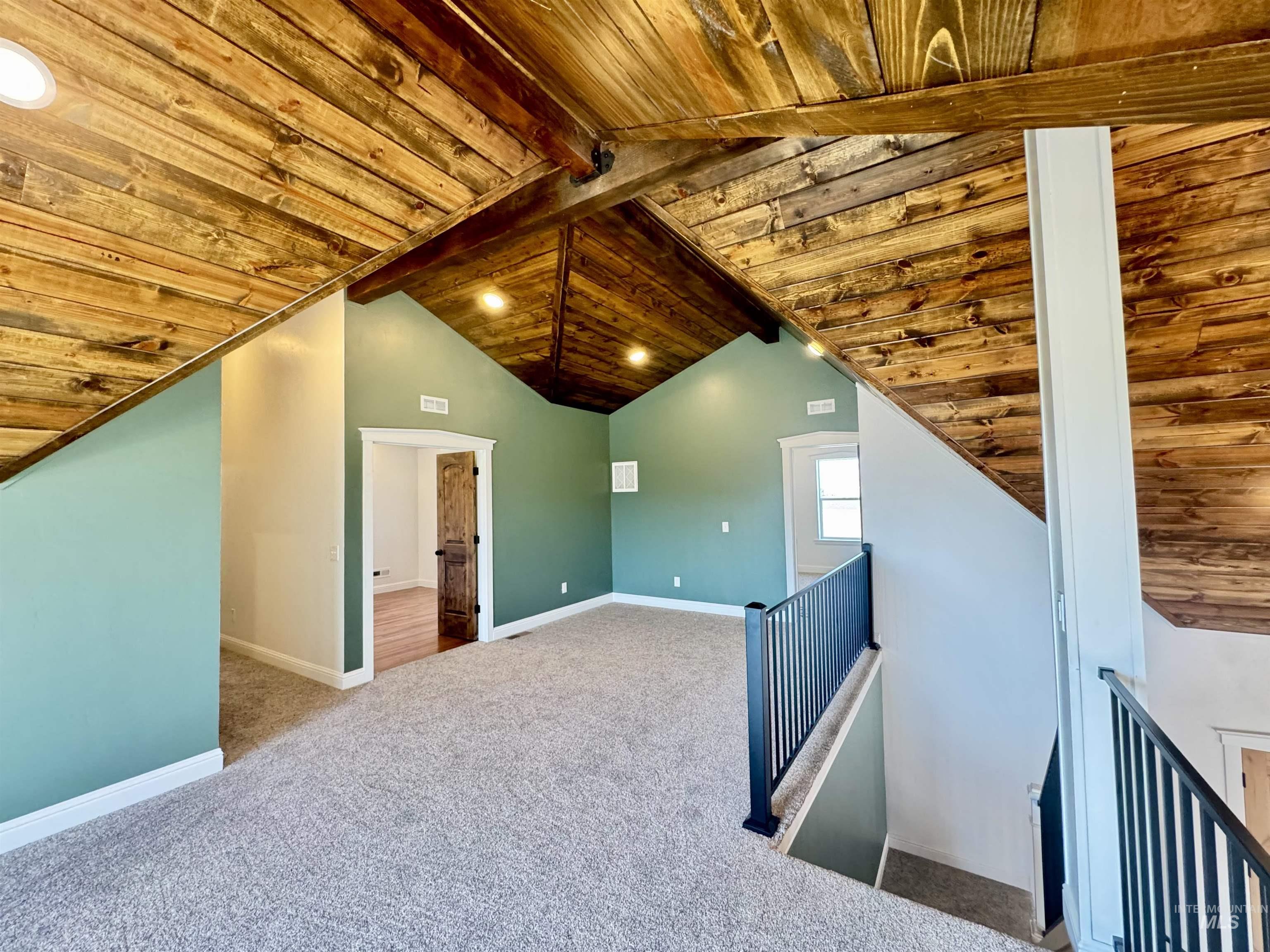 Additional living space with wood ceiling and light colored carpet