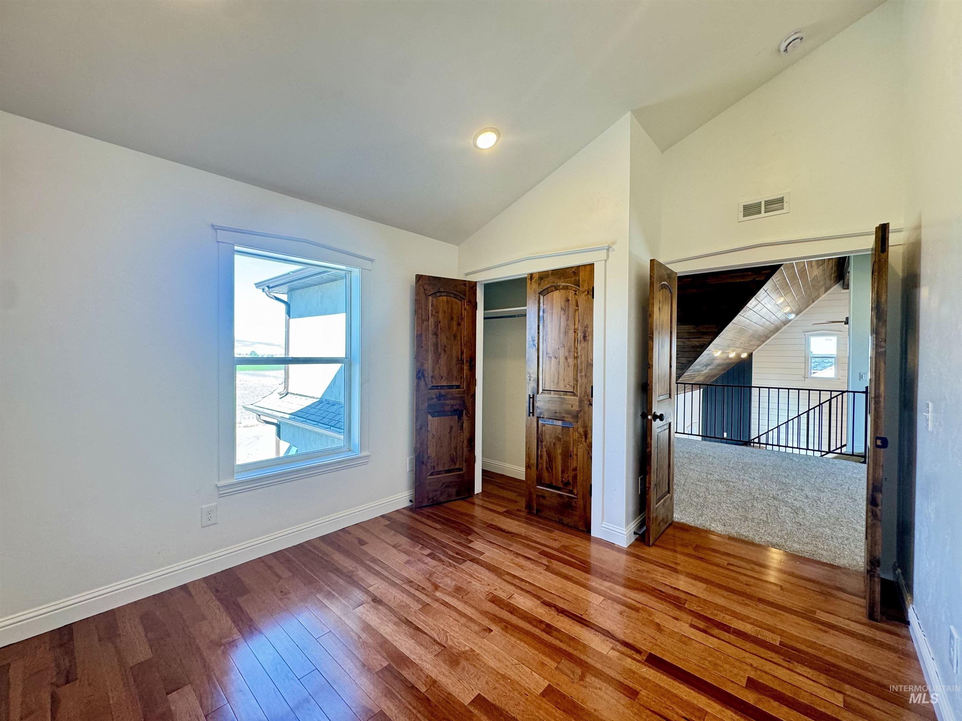 Unfurnished bedroom featuring vaulted ceiling, a closet, wood-type flooring, and recessed lighting