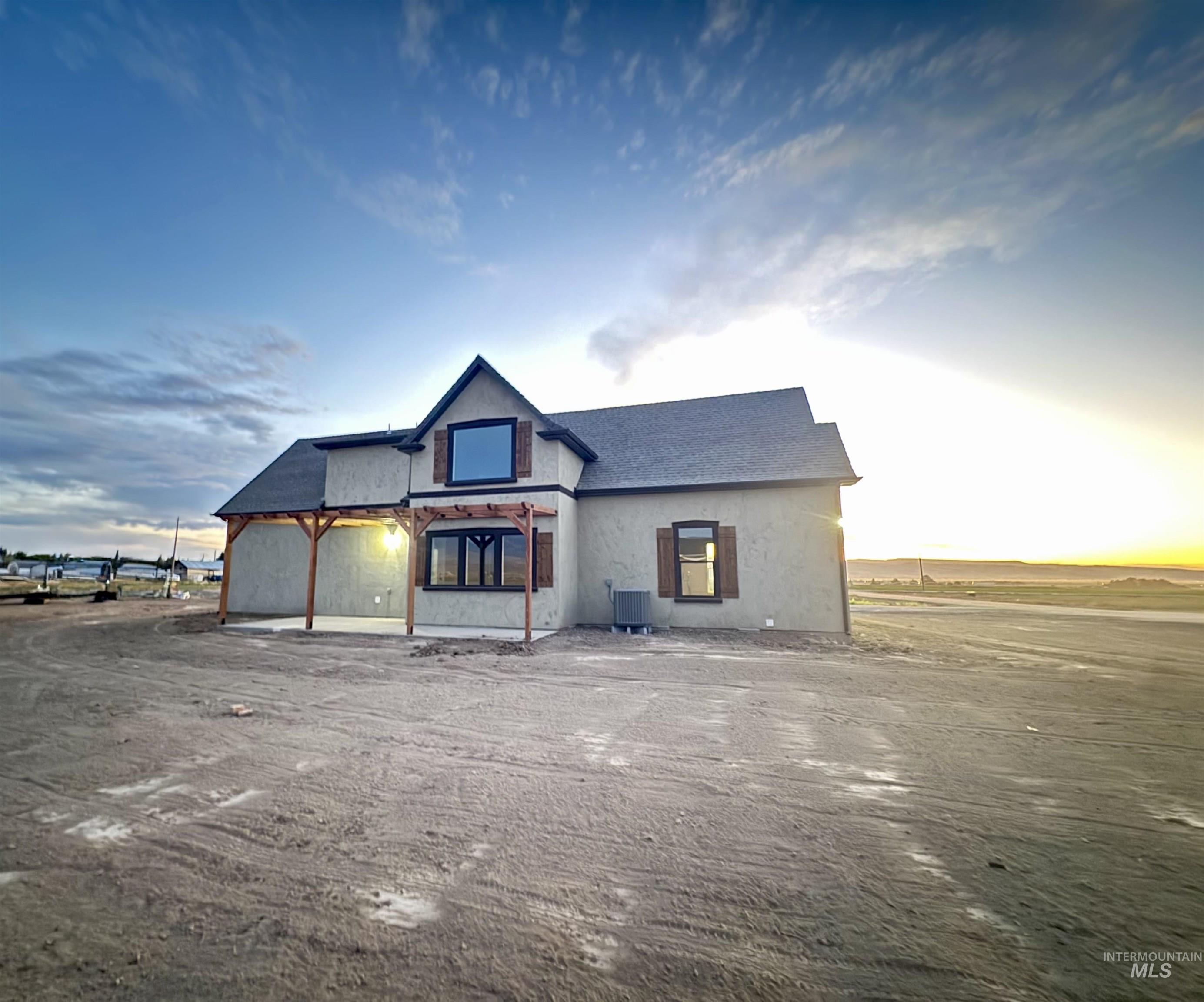 View of front of house with stucco siding, roof with shingles, and a patio