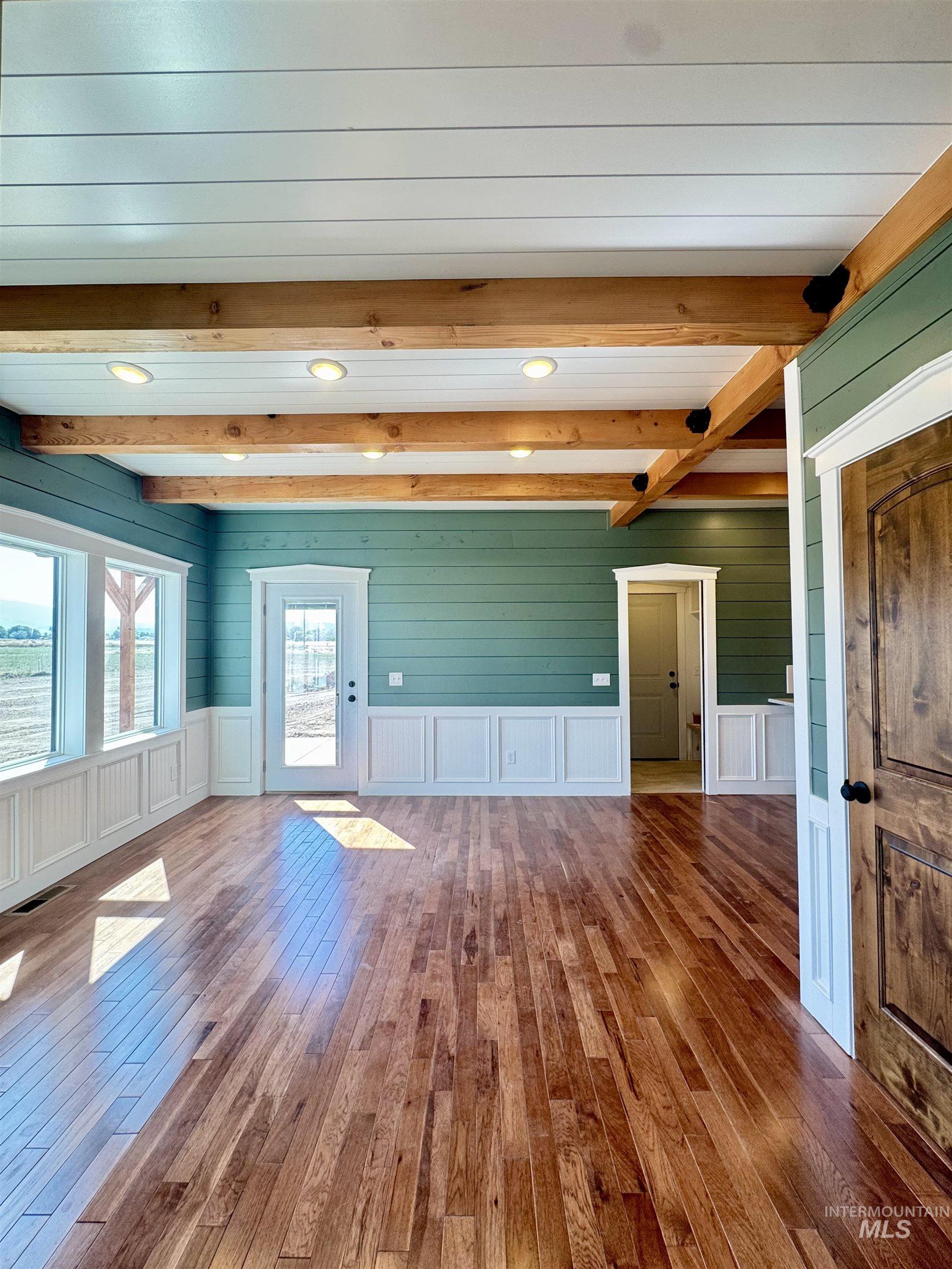 Unfurnished living room with beam ceiling, hardwood / wood-style floors, a decorative wall, and recessed lighting