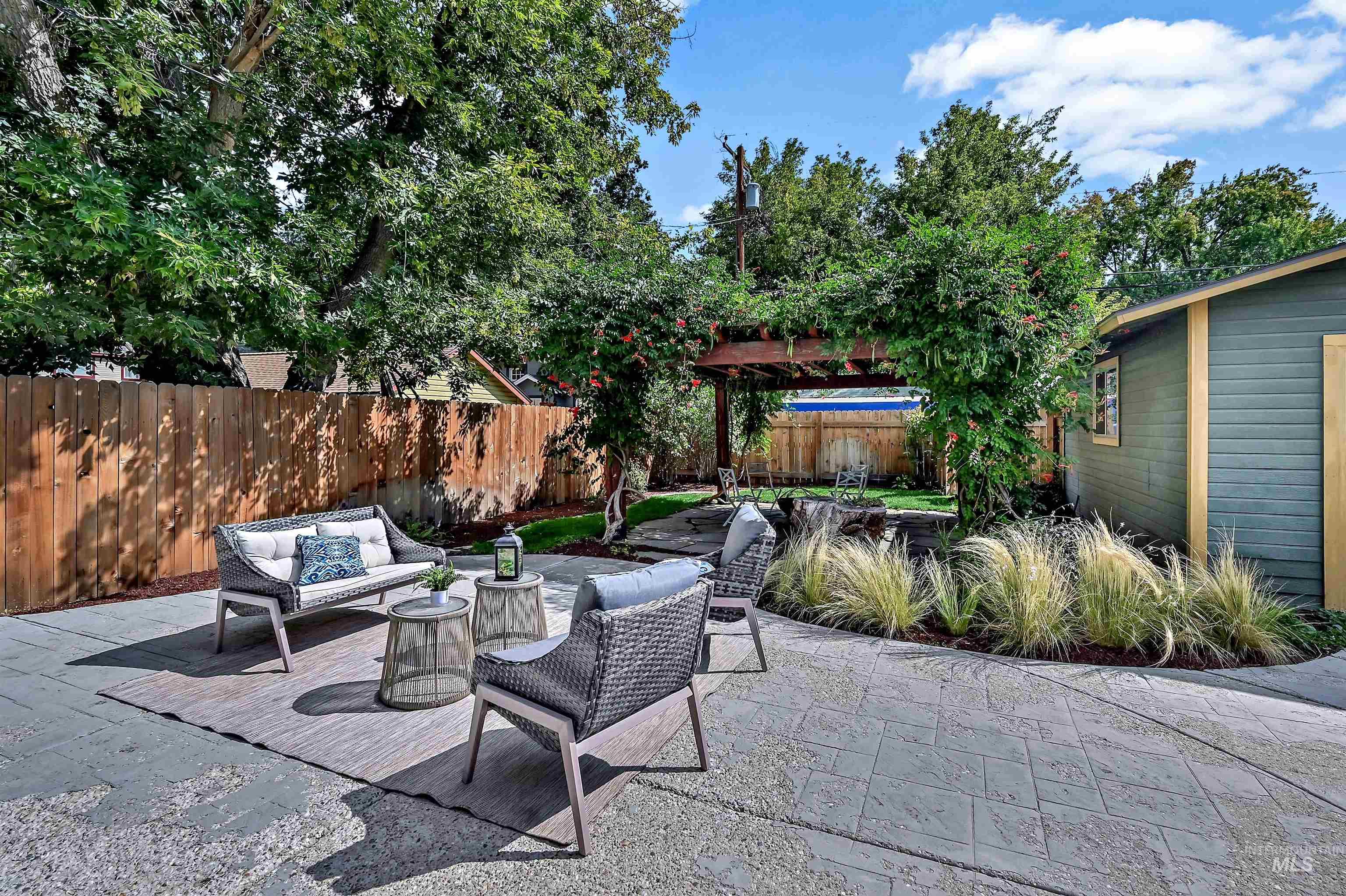 Fenced backyard featuring an outdoor living space and a large concrete patio and a flagstone patio with pergola and fire pit