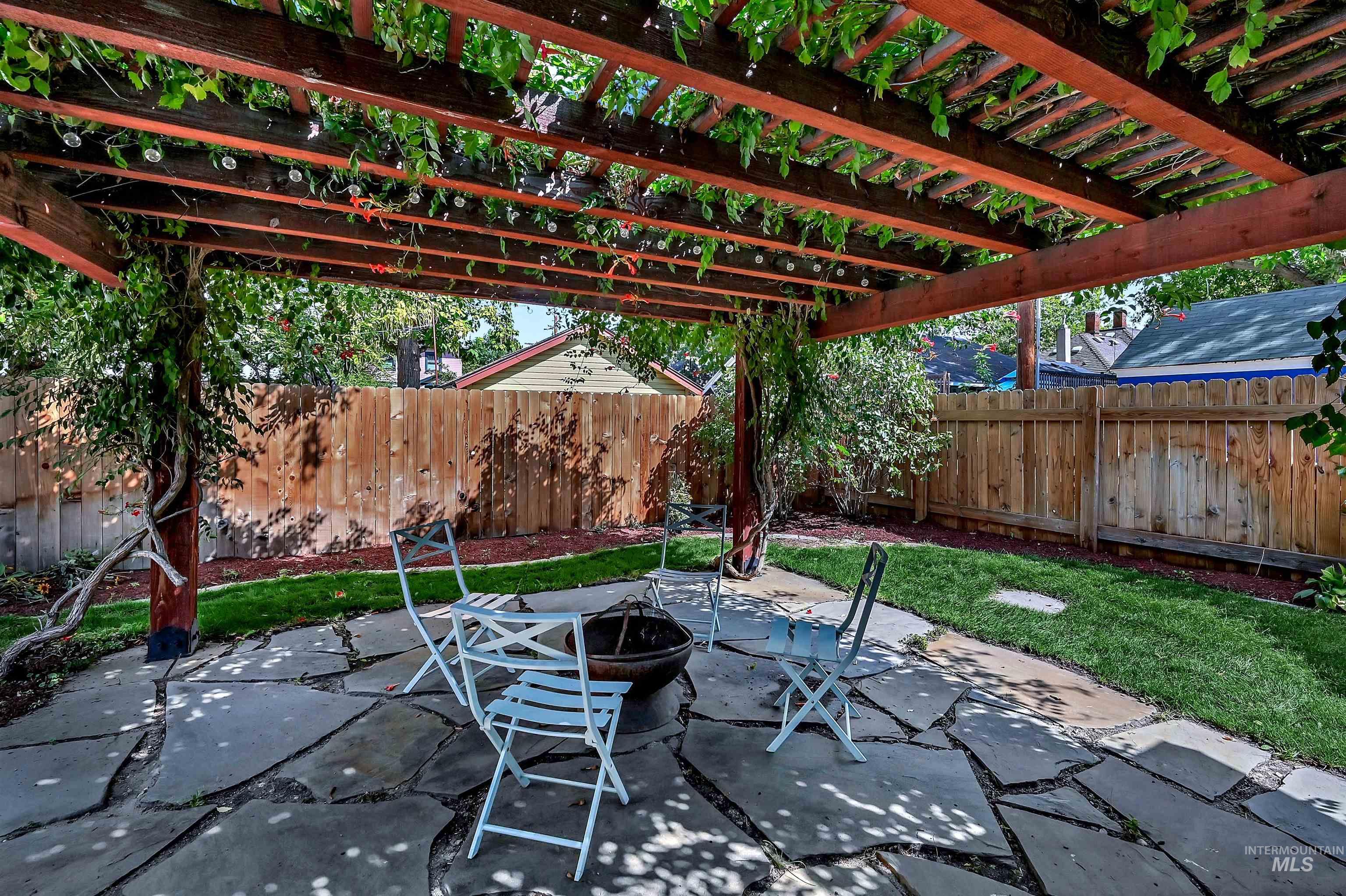Fenced backyard featuring an outdoor living space and a large concrete patio and a flagstone patio with pergola and fire pit