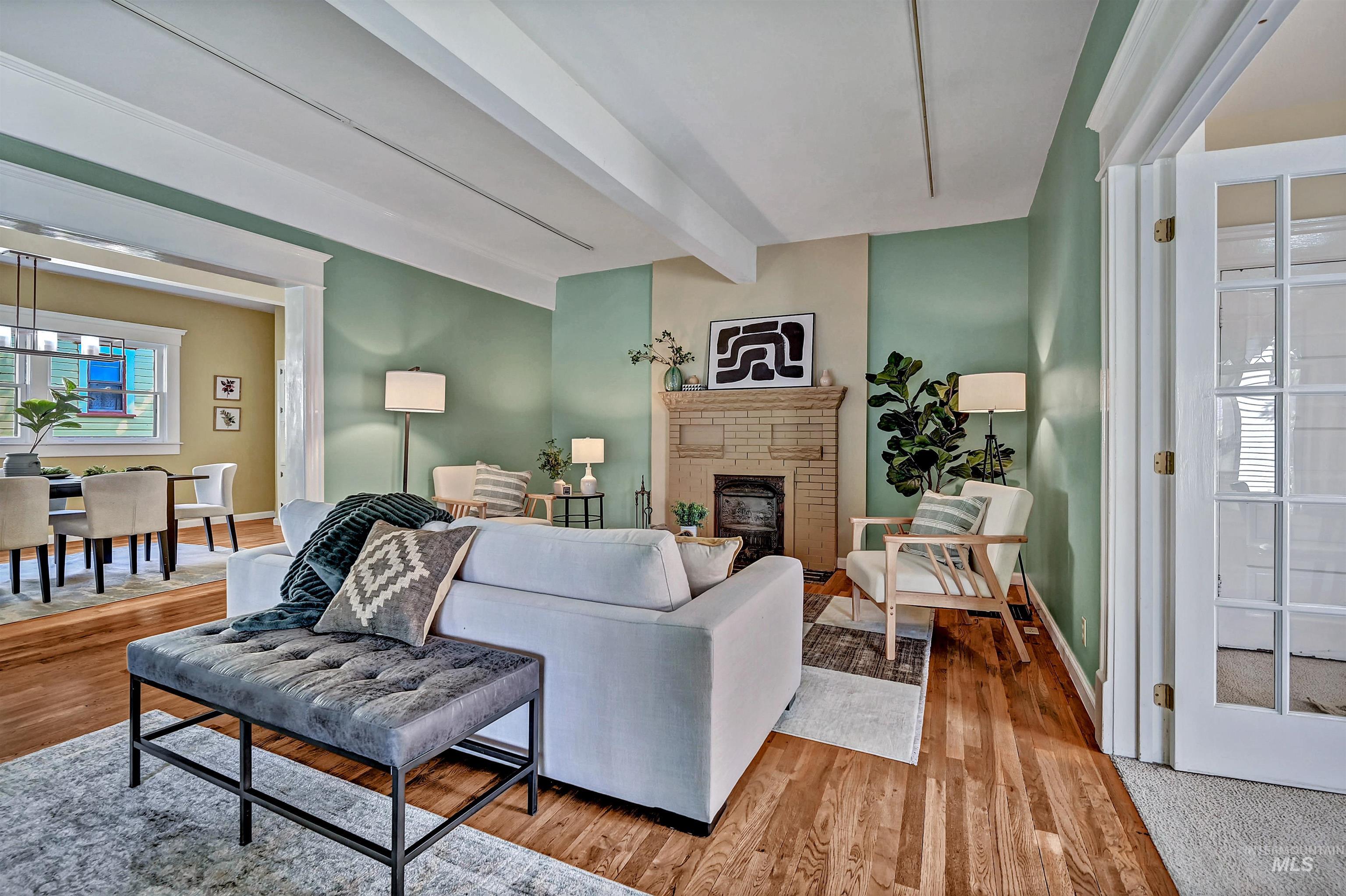 Living room with beamed ceiling, original wood floors, and an historic Dawson Brothers cast-iron fireplace.