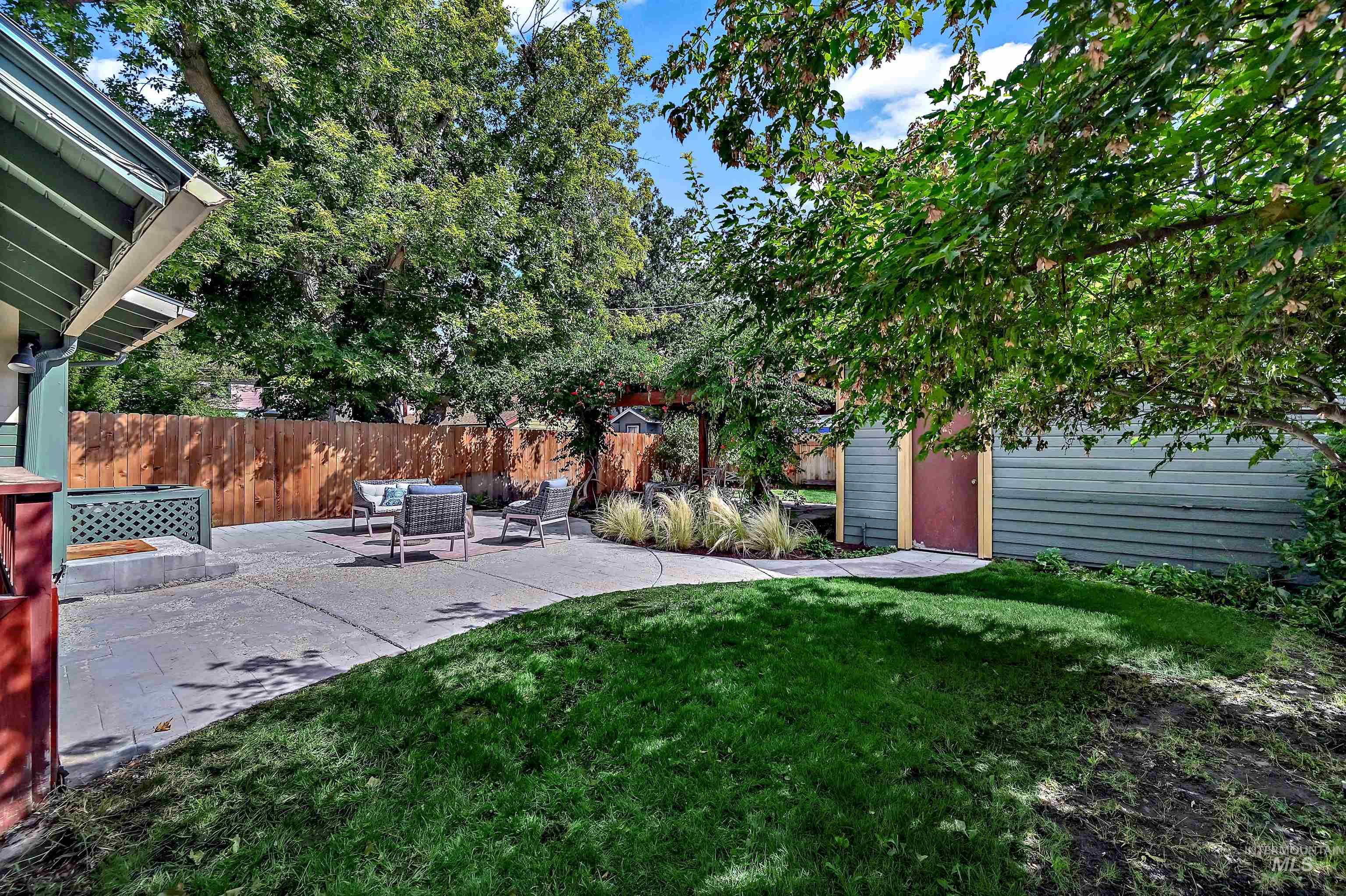 Fenced backyard featuring an outdoor living space and a large concrete patio and a flagstone patio with pergola and fire pit