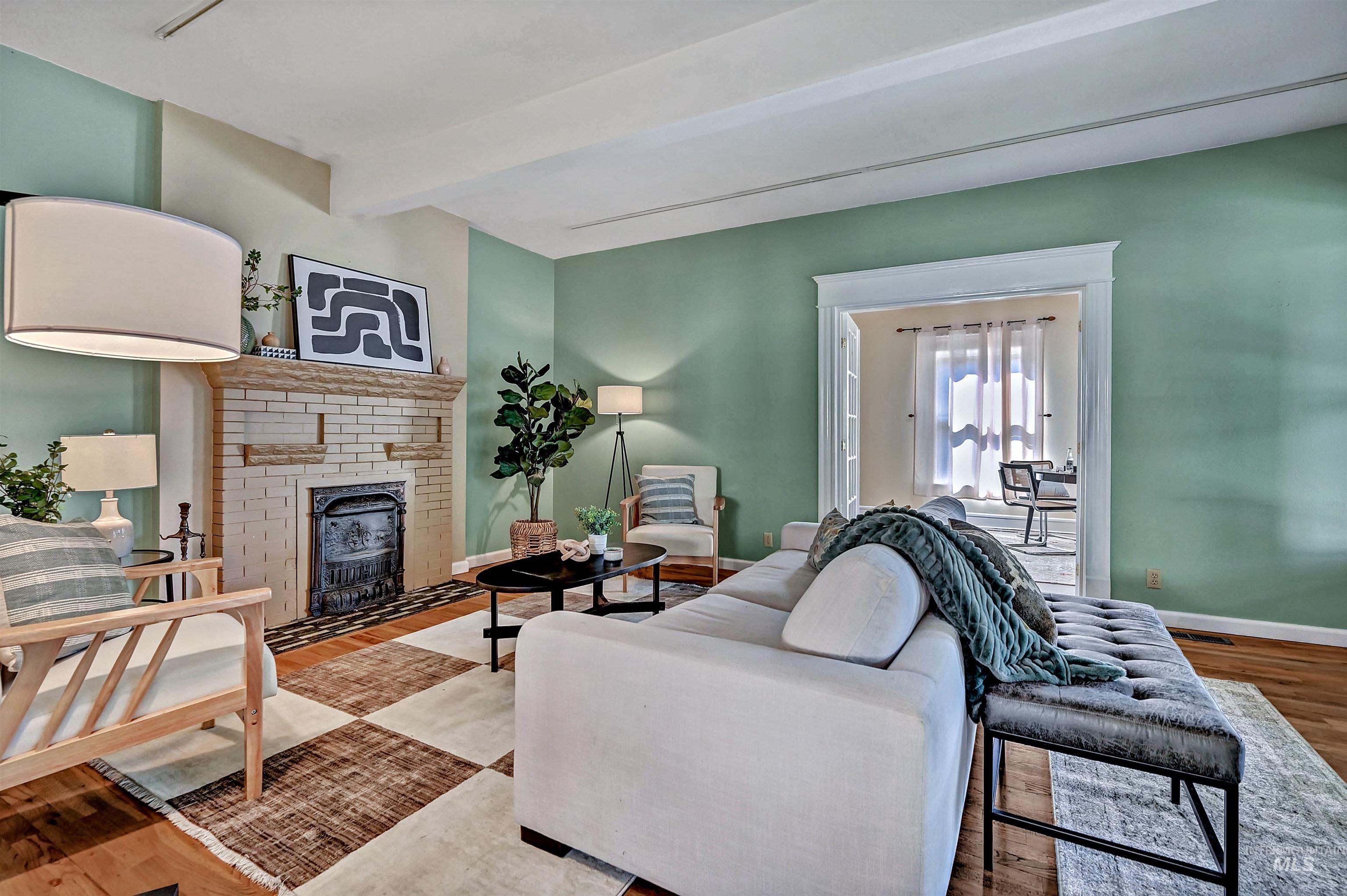 Living room with beamed ceiling, original wood floors, and an historic Dawson Brothers cast-iron fireplace.