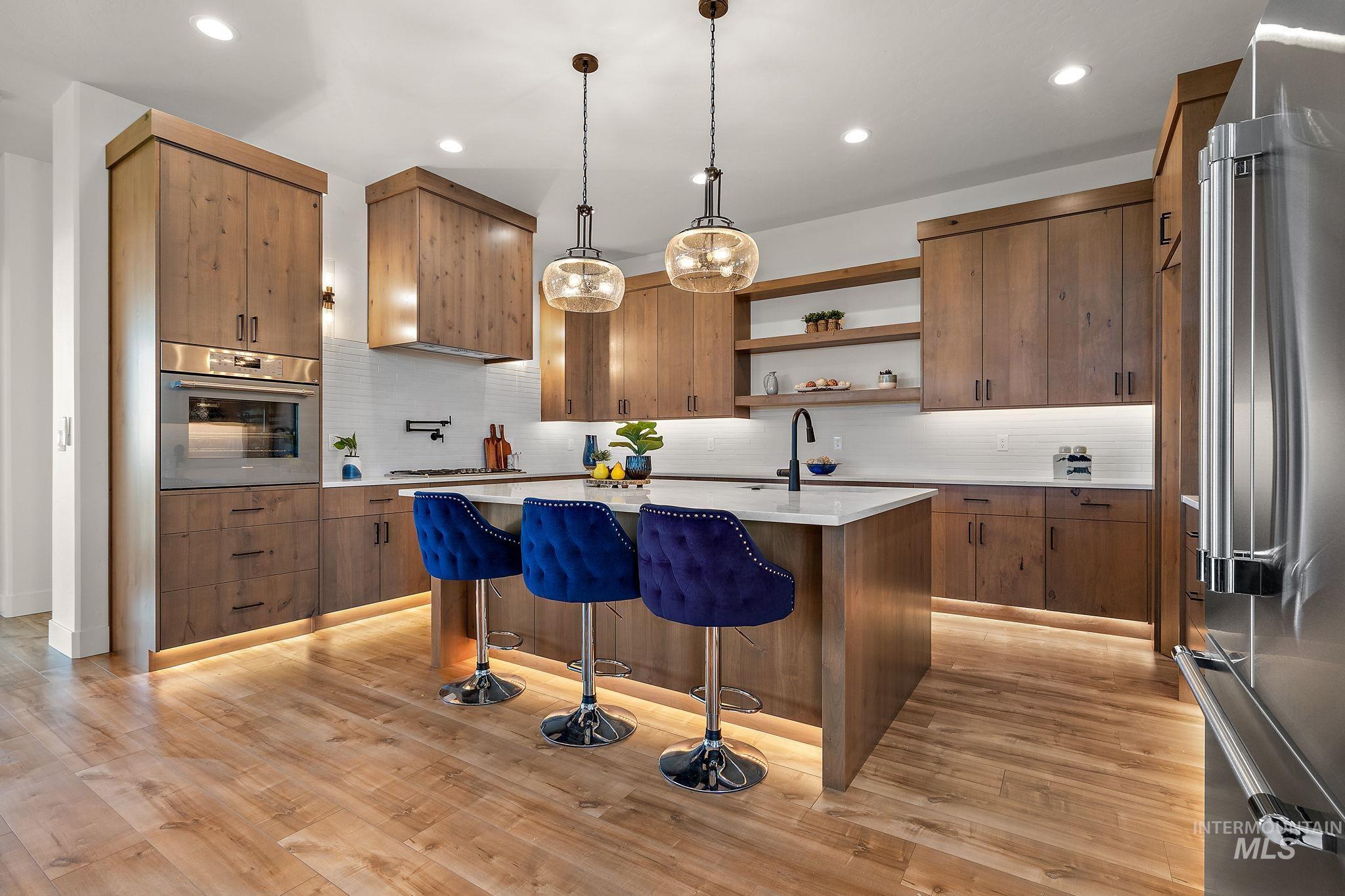 Kitchen featuring open shelves, appliances with stainless steel finishes, a breakfast bar, pendant lighting, and backsplash
