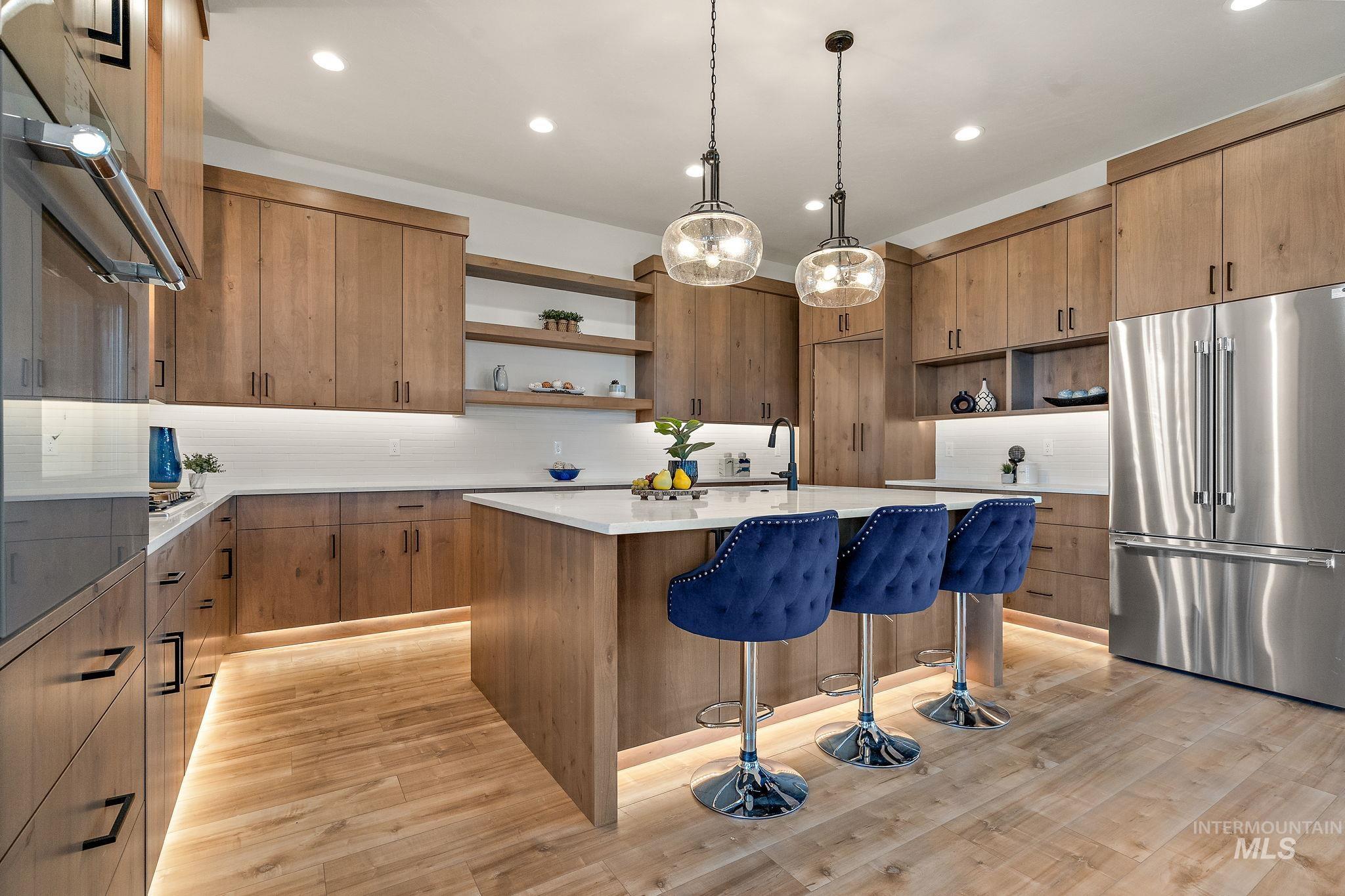 Kitchen with open shelves, a breakfast bar area, appliances with stainless steel finishes, brown cabinets, and backsplash