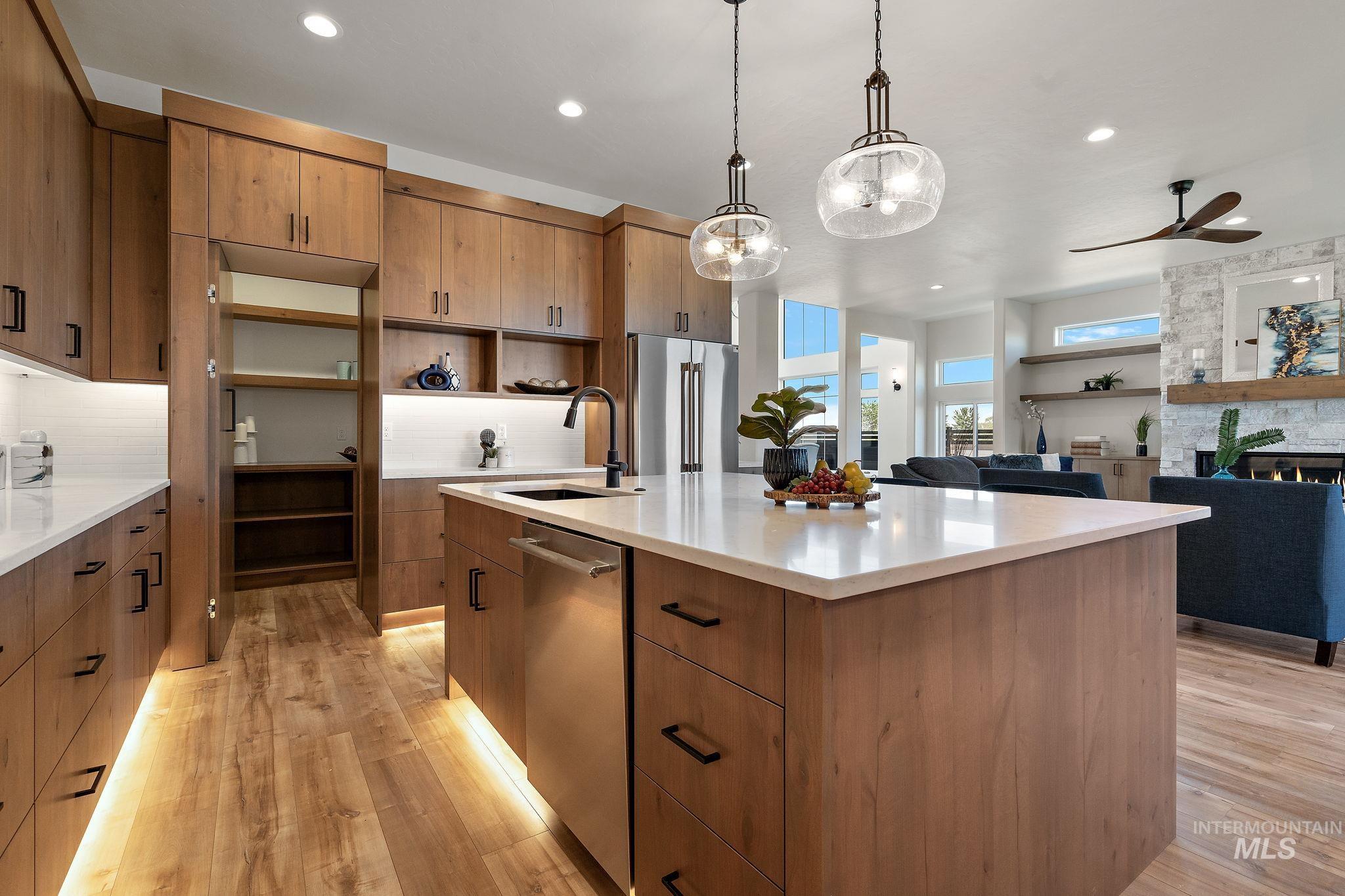Kitchen featuring decorative light fixtures, open floor plan, light stone countertops, stainless steel appliances, and recessed lighting