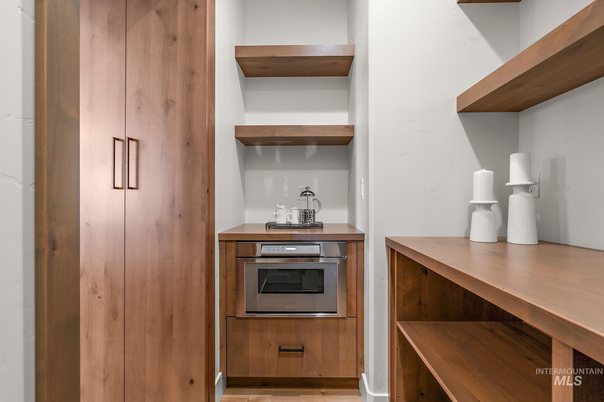 Kitchen with open shelves, stainless steel oven, and light wood-type flooring